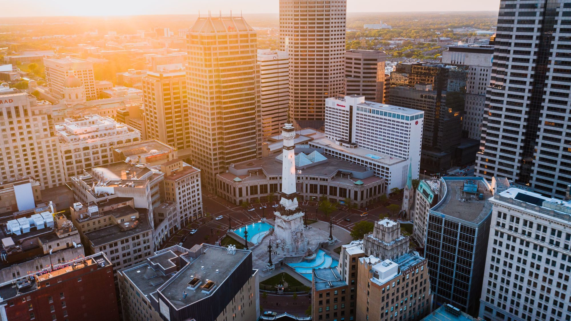 Downtown Indianapolis towers seen from above in warm evening light.