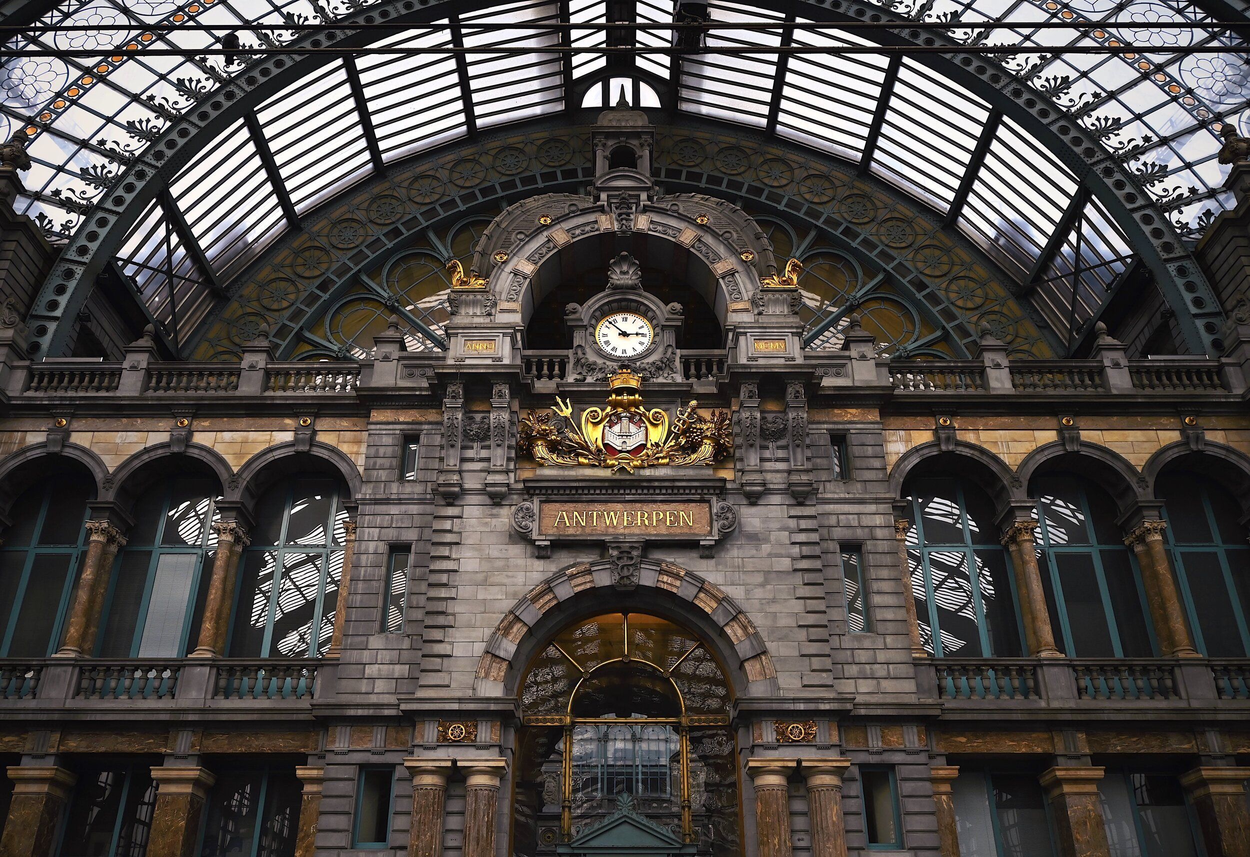 The grand entrance hall of Antwerp Central Station with its clock and iron-and-glass roof.