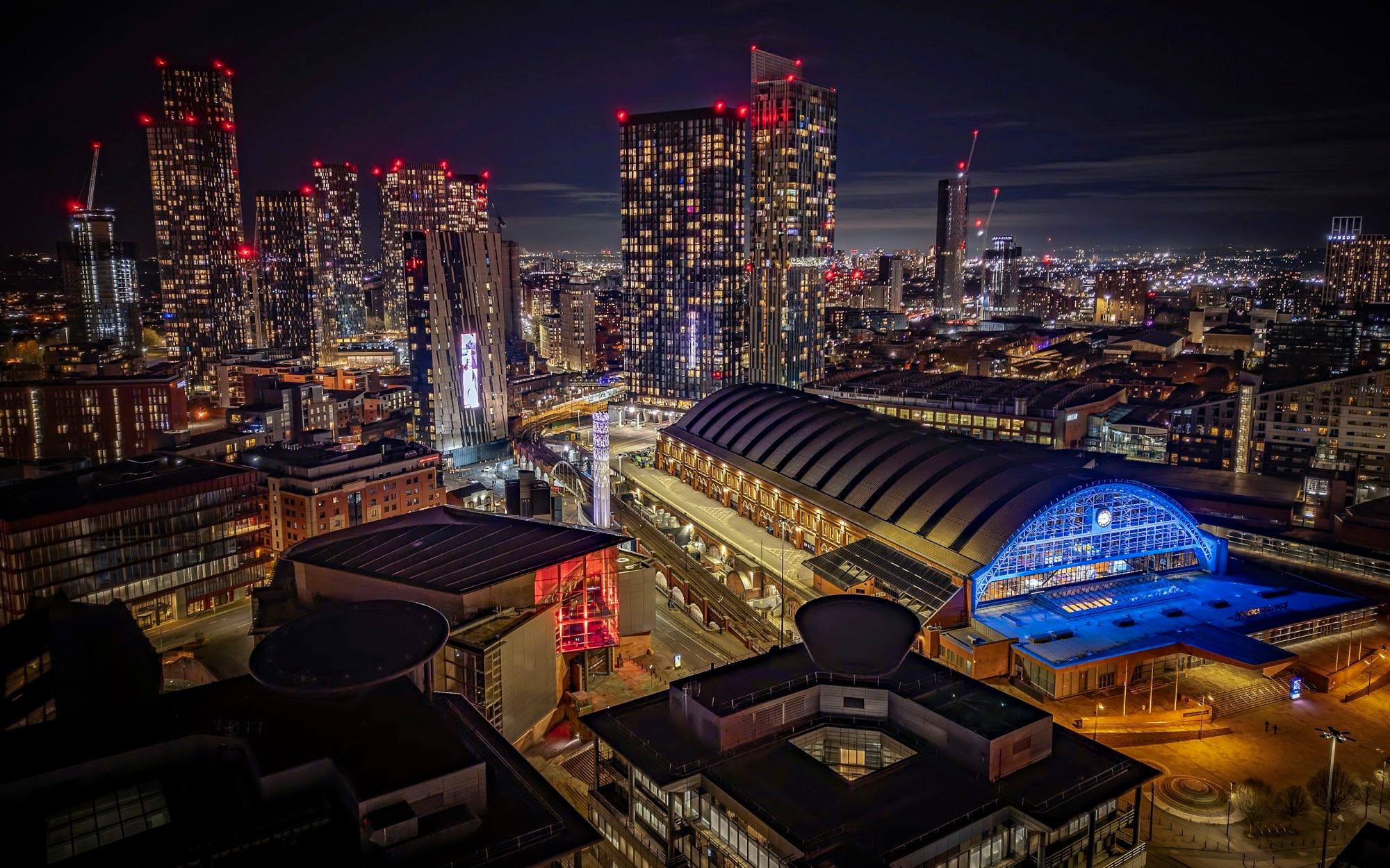 Manchester’s skyline at night, with the lit arched roof of Manchester Central in front of the Deansgate Square towers