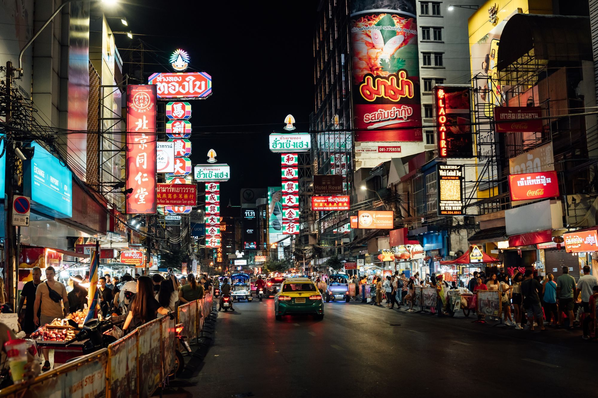 Yaowarat Road in Bangkok's Chinatown at night, with food stalls, neon signs and people walking in the street.
