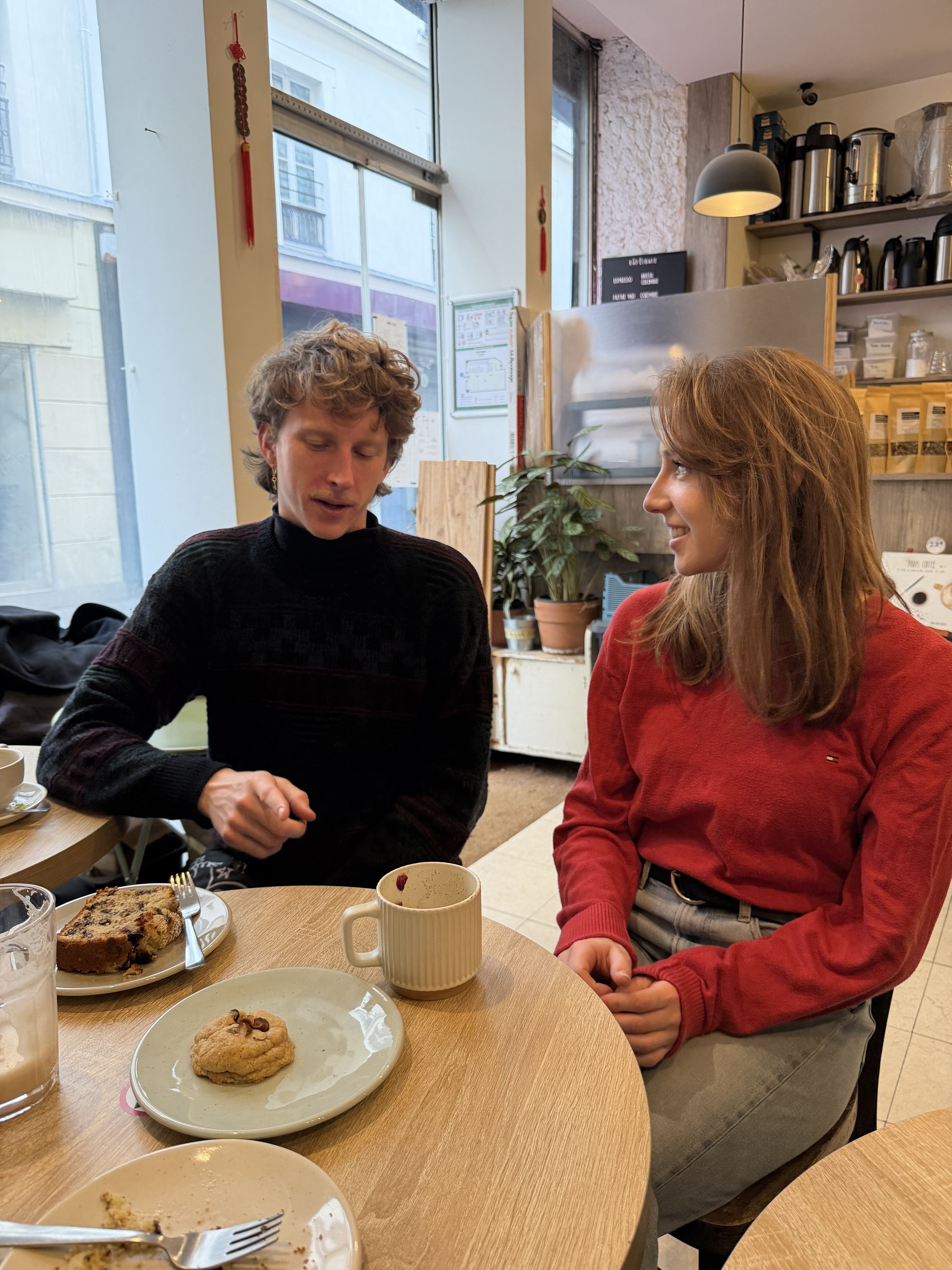 Two people talking over coffee and pastries in a bright café