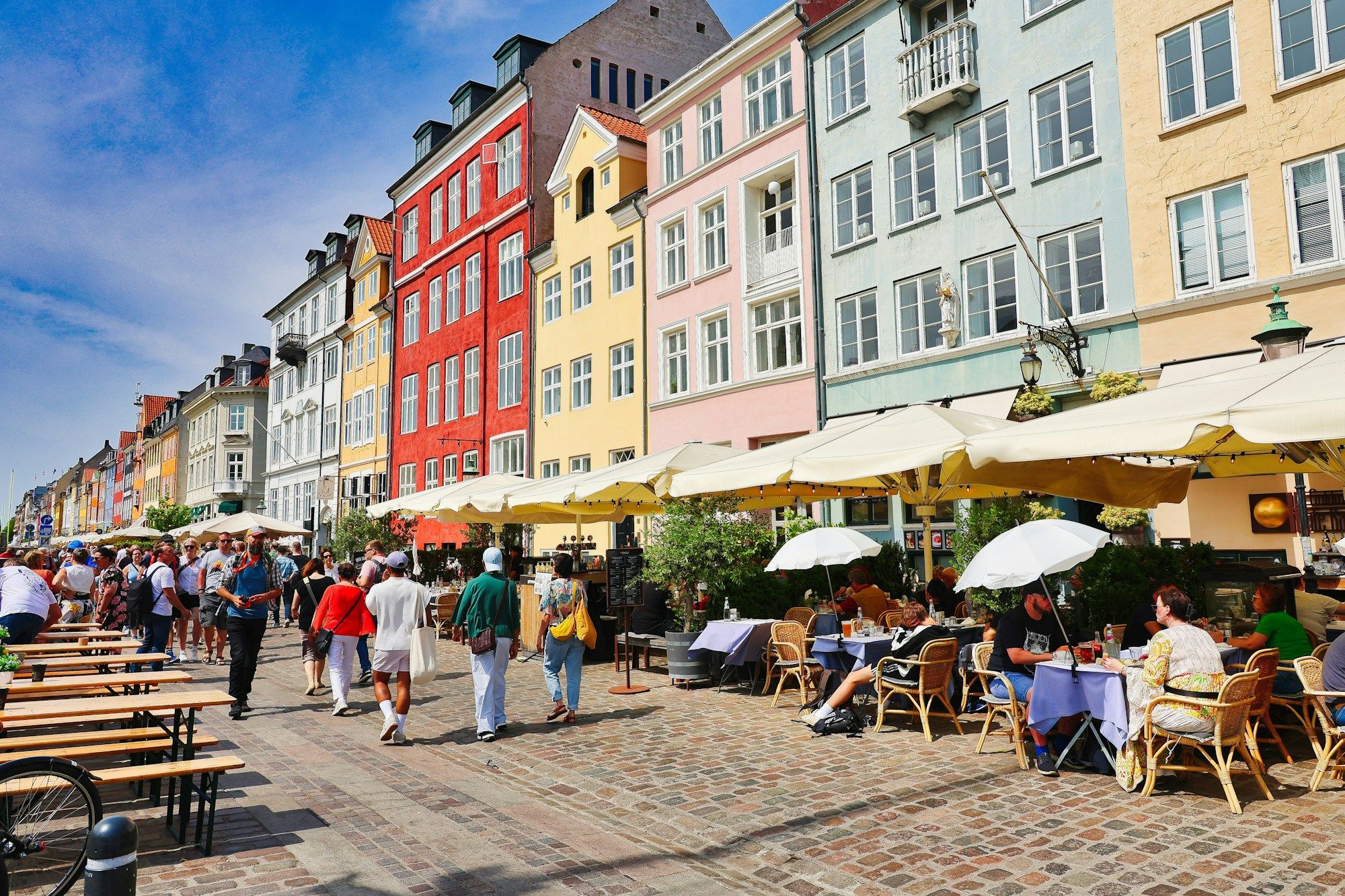 People at café tables under umbrellas along Nyhavn in Copenhagen