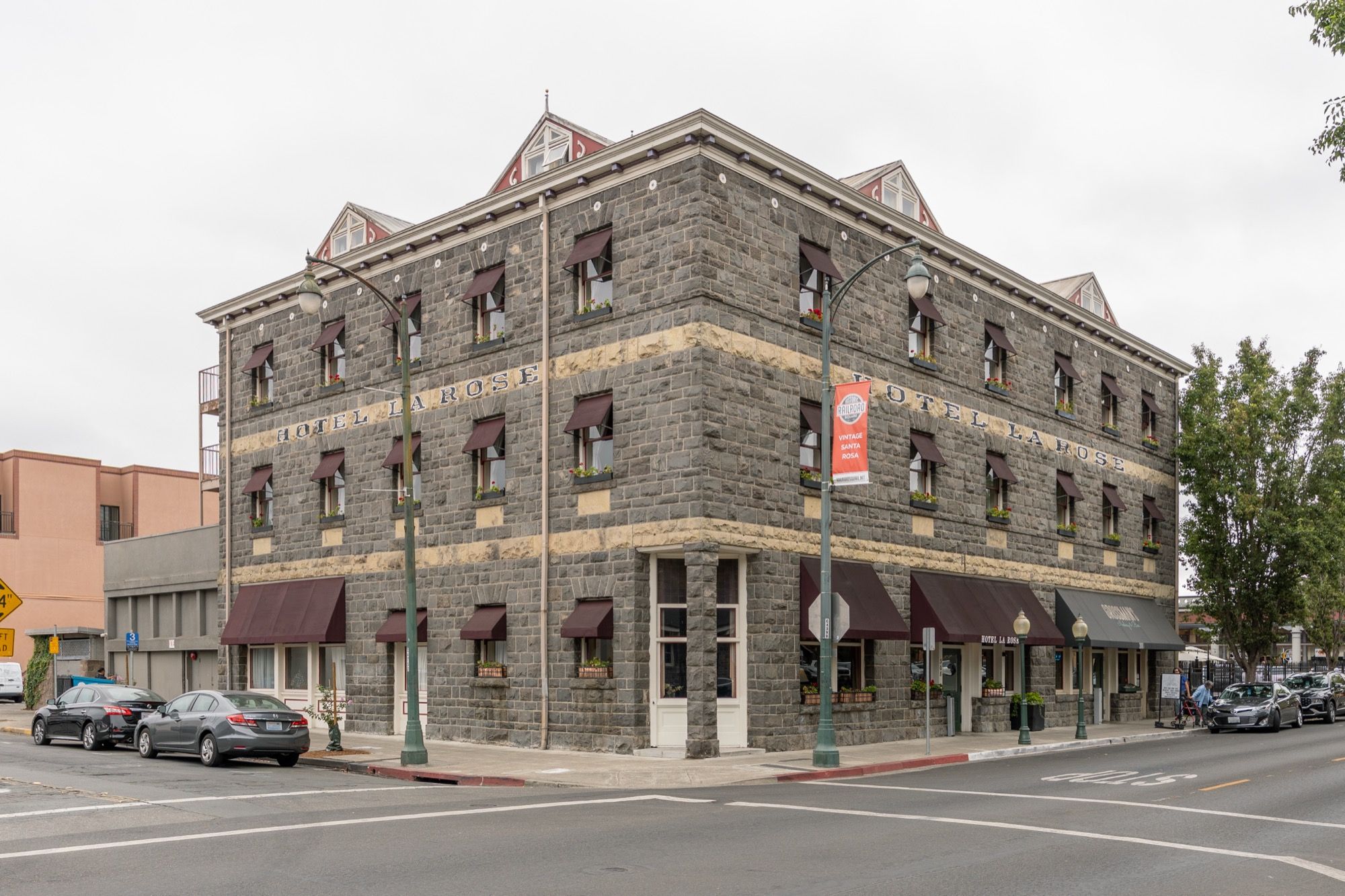 The stone exterior of Hotel La Rose on a street corner in Santa Rosa.