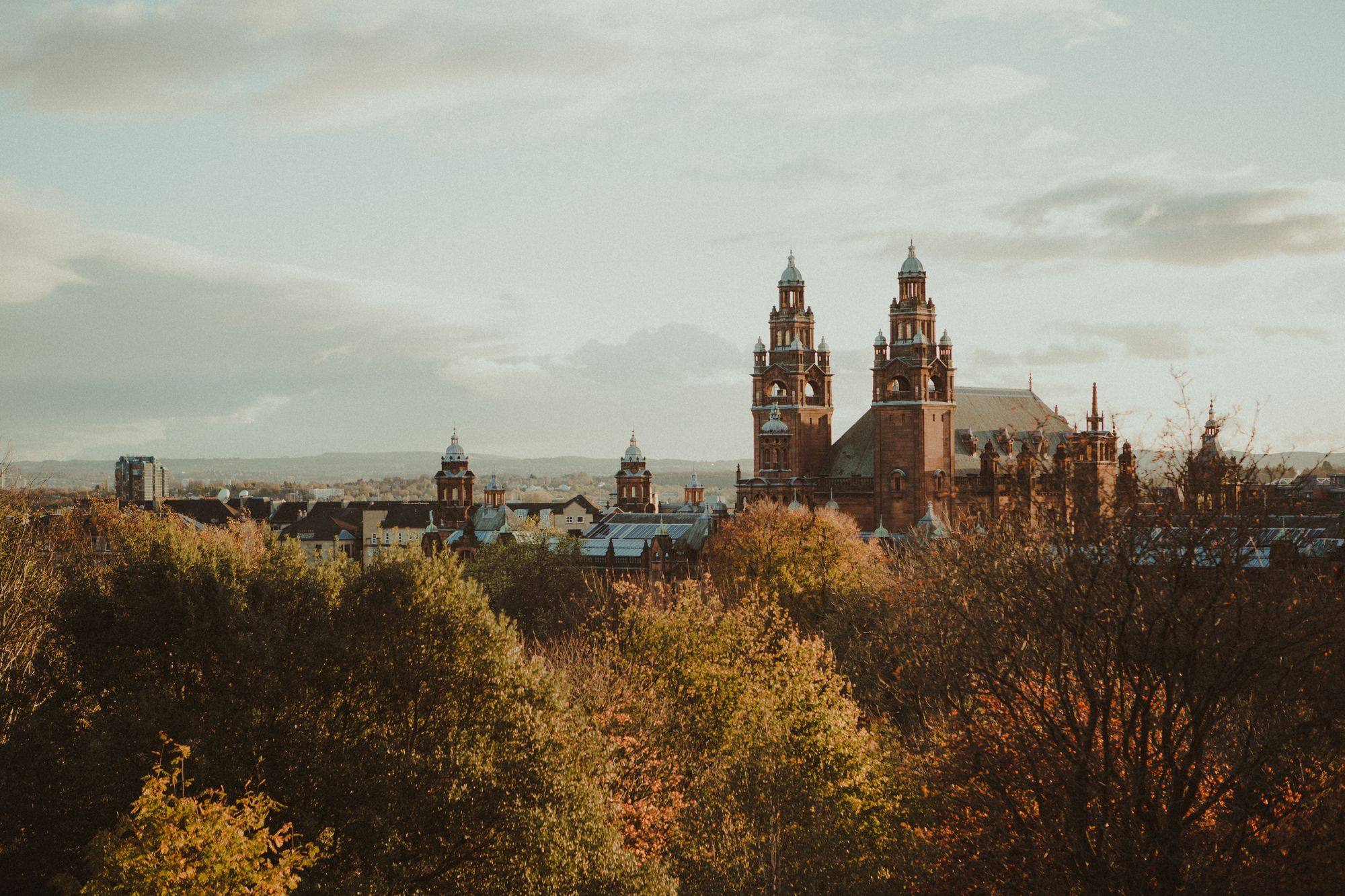 The red sandstone towers of Kelvingrove Art Gallery and Museum above autumn trees in Glasgow.