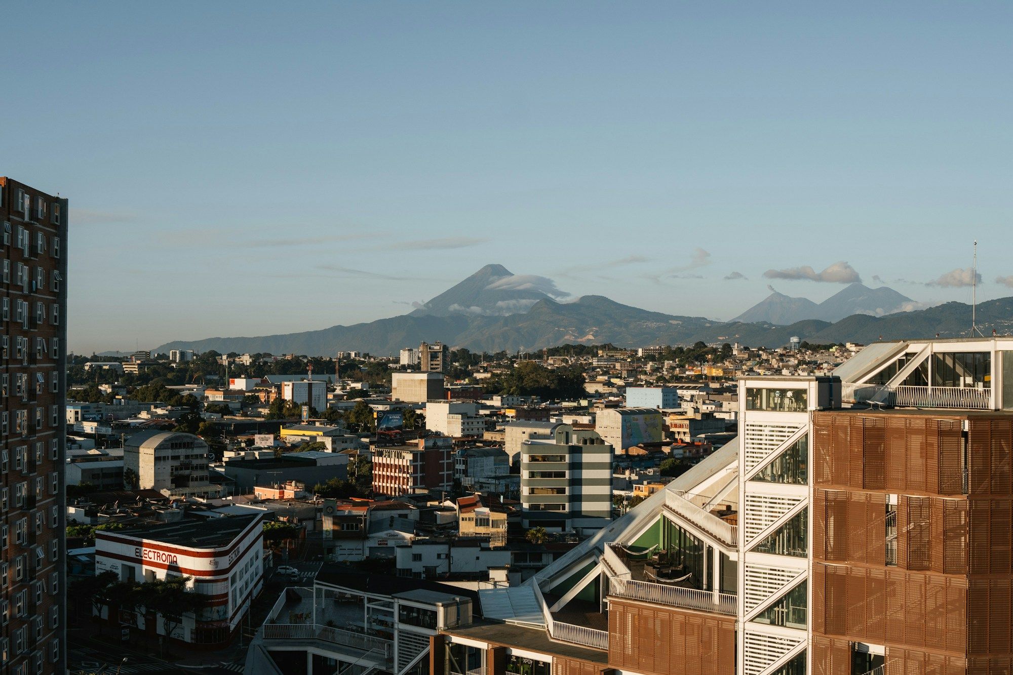 Rooftops in Guatemala City with volcanoes on the horizon