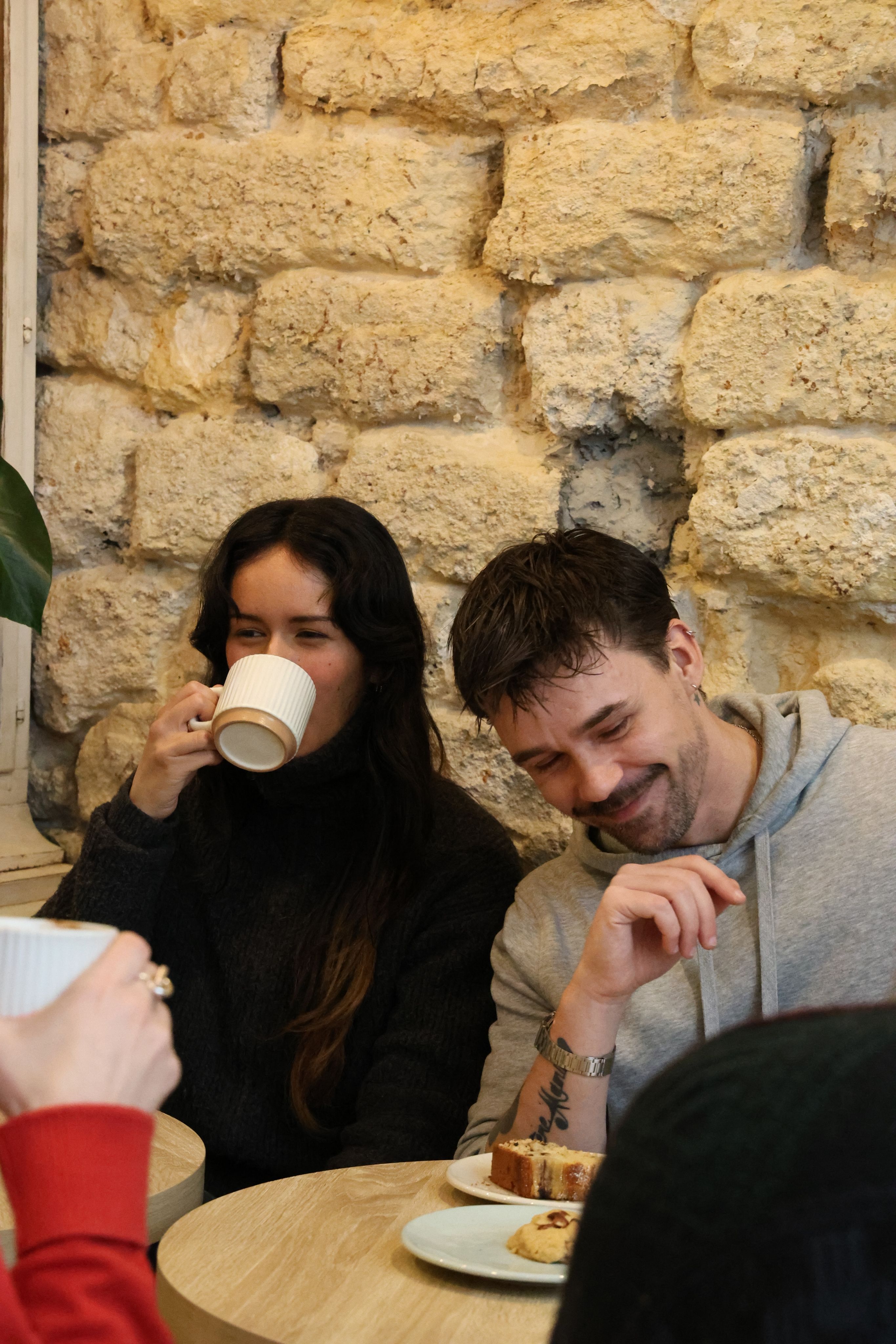 Two people chatting over coffee and cake in a stone-walled café