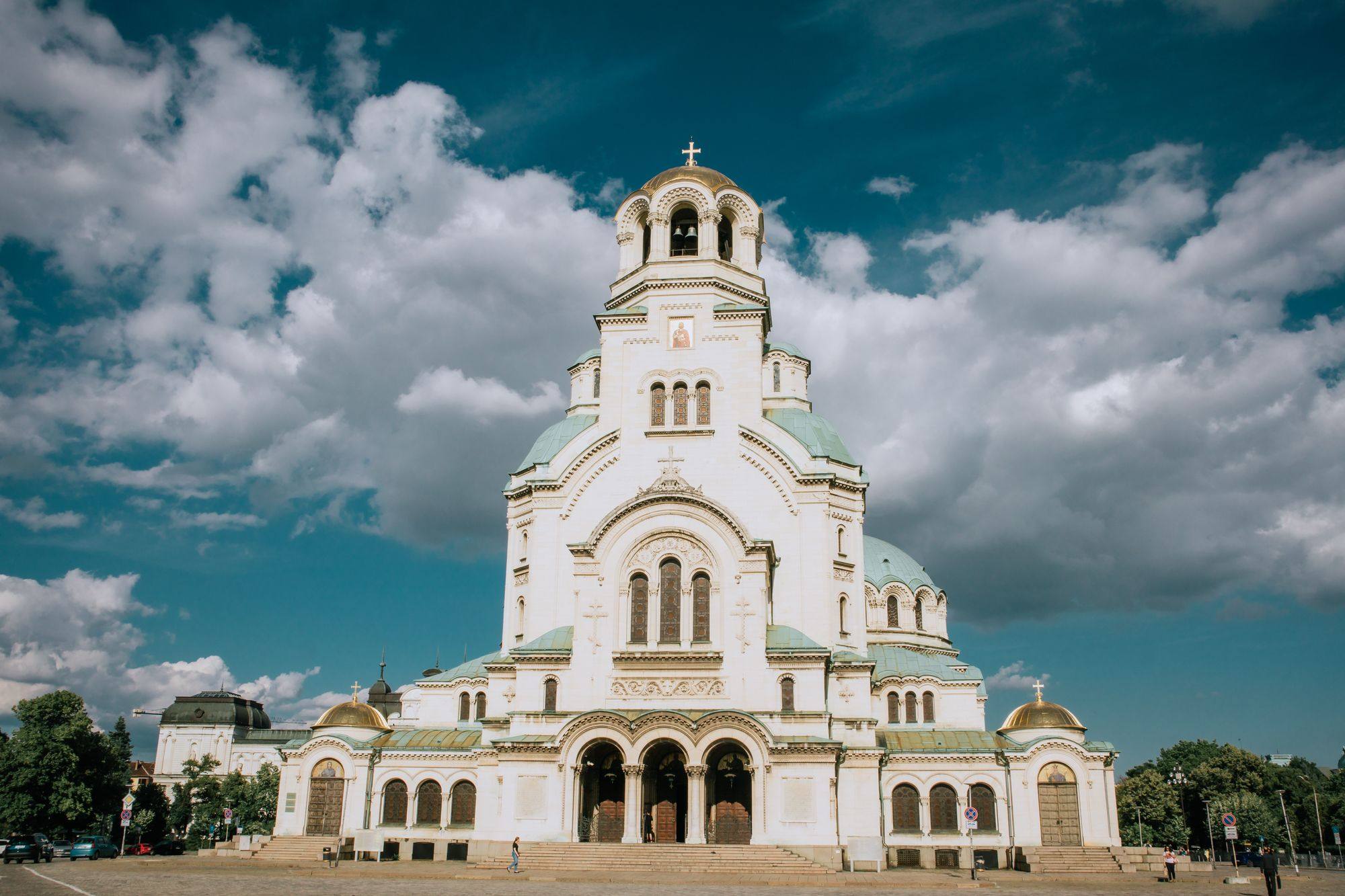 Alexander Nevsky Cathedral in Sofia seen from the front under a blue sky with large clouds.
