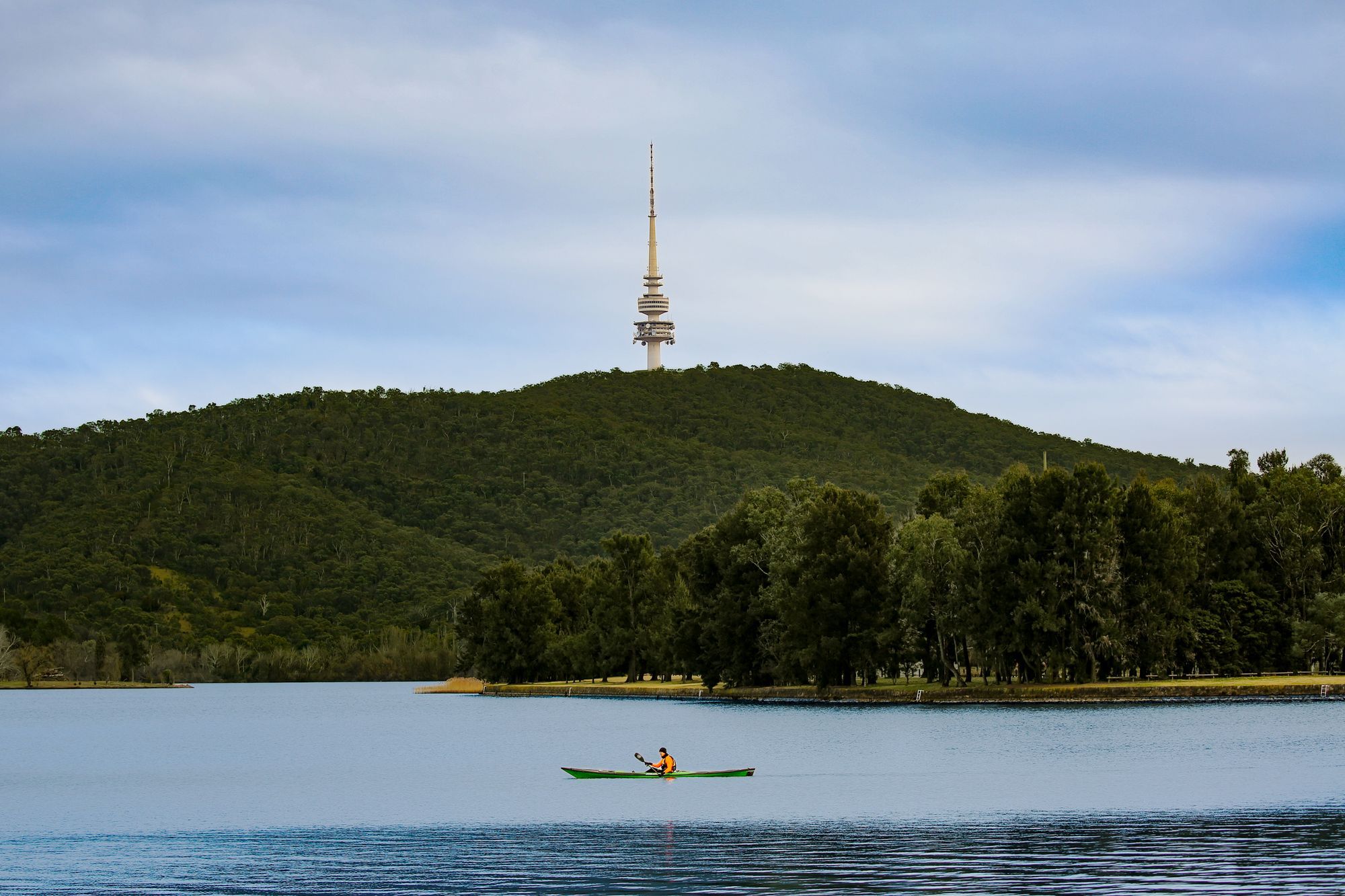 A kayaker on Lake Burley Griffin in Canberra, with Telstra Tower on Black Mountain in the background.