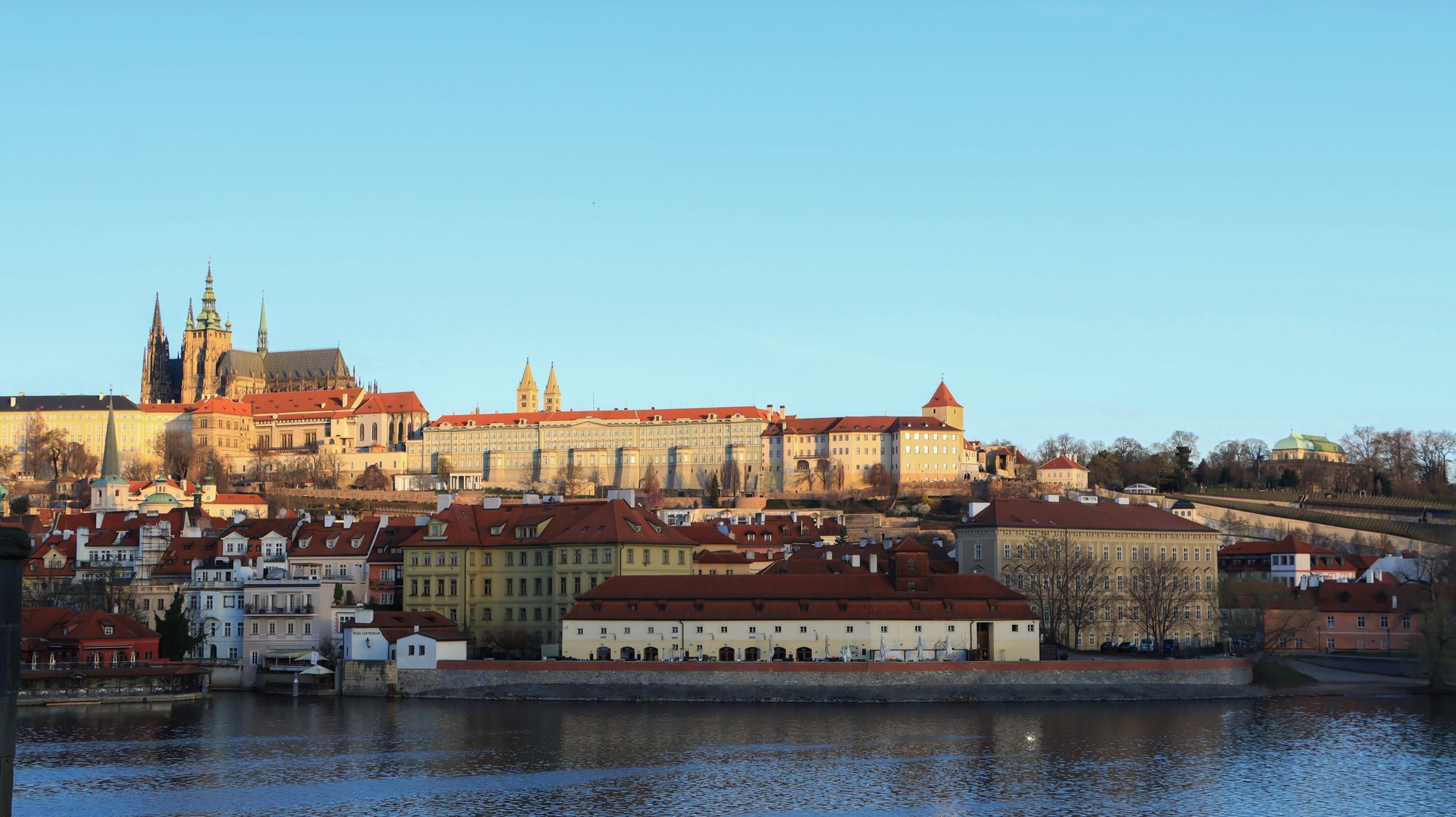 Prague Castle on its hill above the Vltava river, seen from across the water.