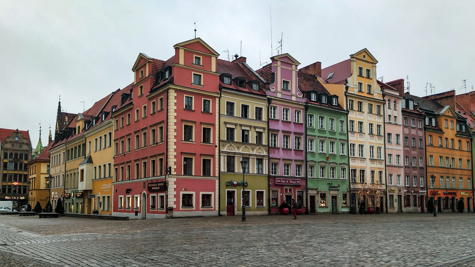 A row of coloured tenement houses on Market Square in Wrocław under a pale sky.