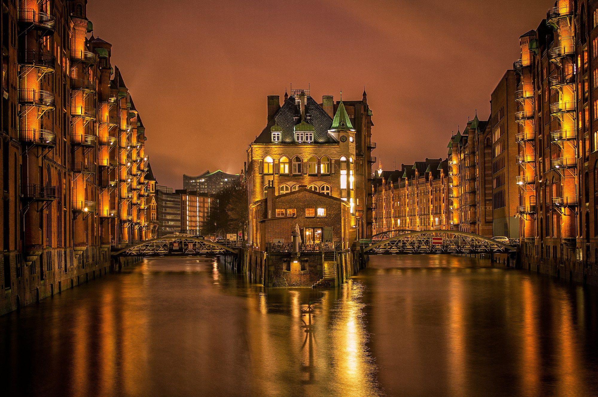 The Wasserschloss lit up at dusk between the brick warehouses of Hamburg's Speicherstadt