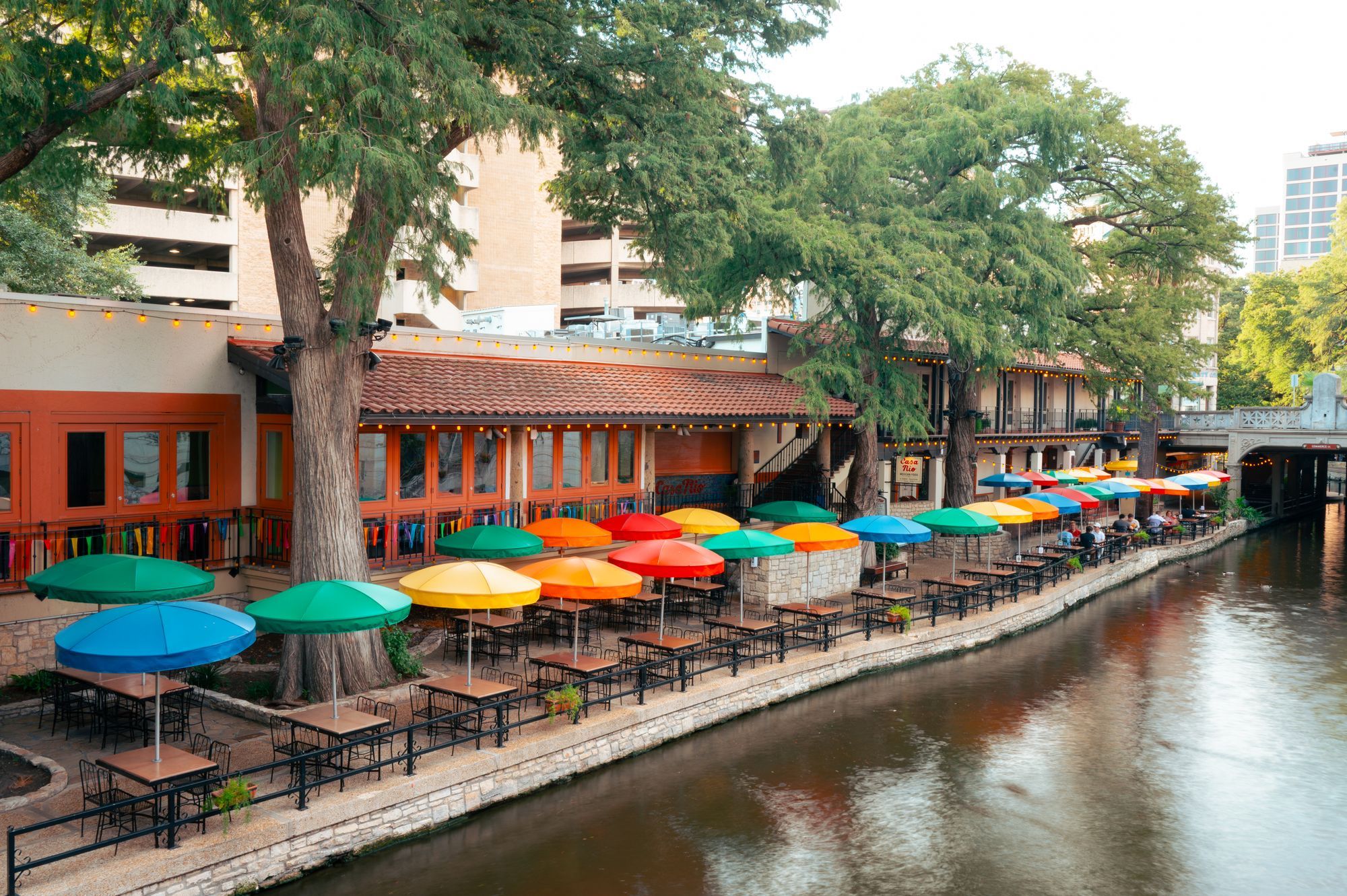 Colorful umbrellas over restaurant tables along the River Walk in San Antonio.