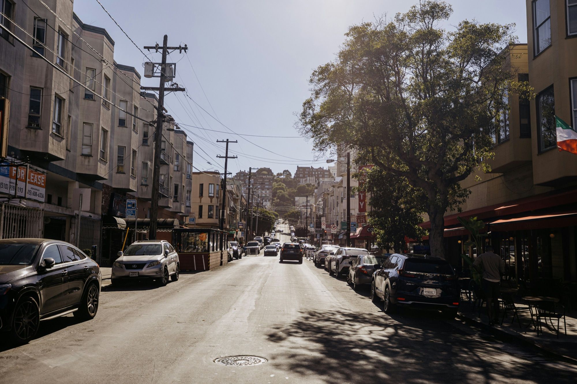 A sunny street in North Beach, San Francisco, with cars parked along it