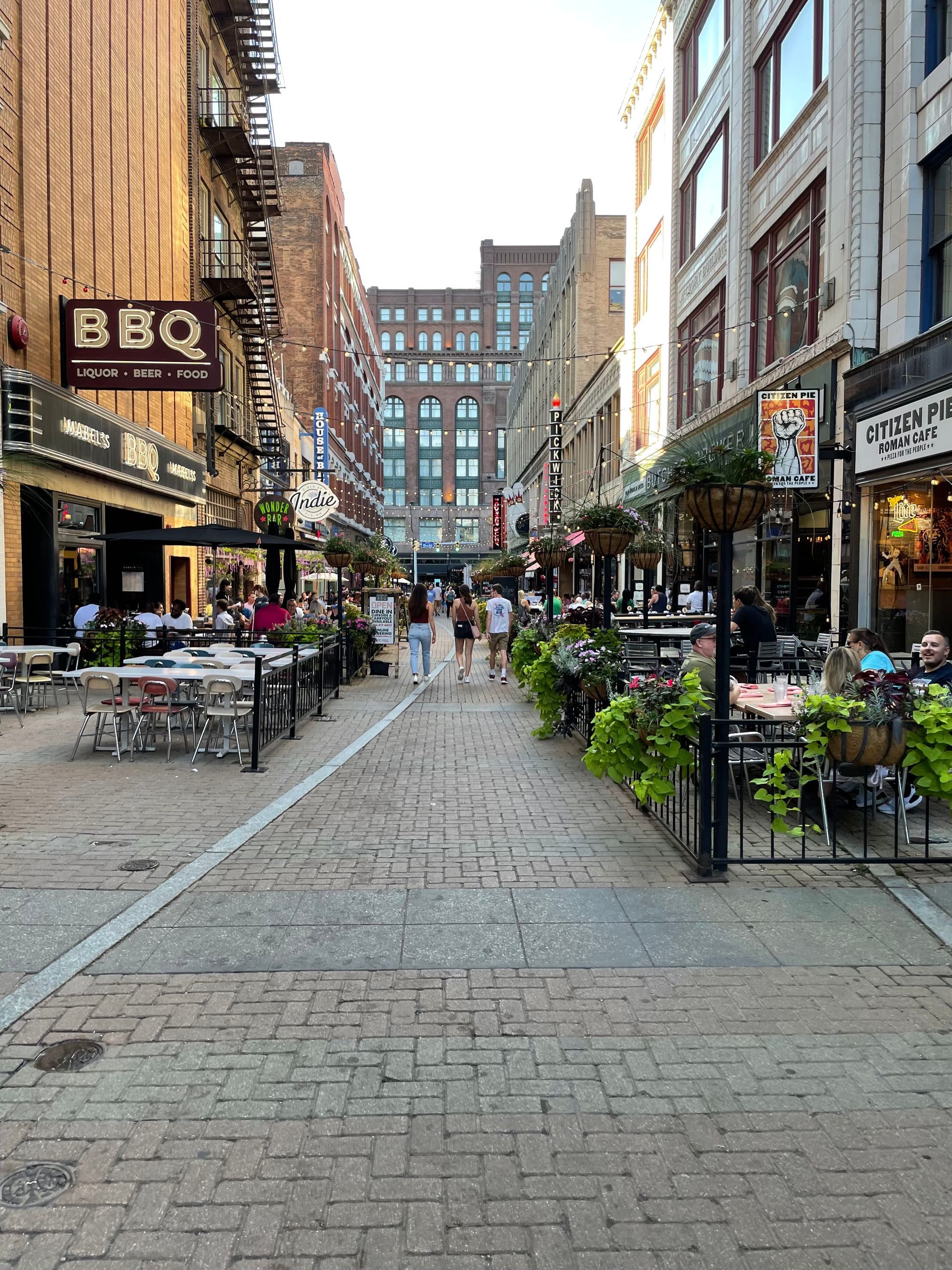 A pedestrian brick street with restaurant patios and walkers in downtown Cleveland.