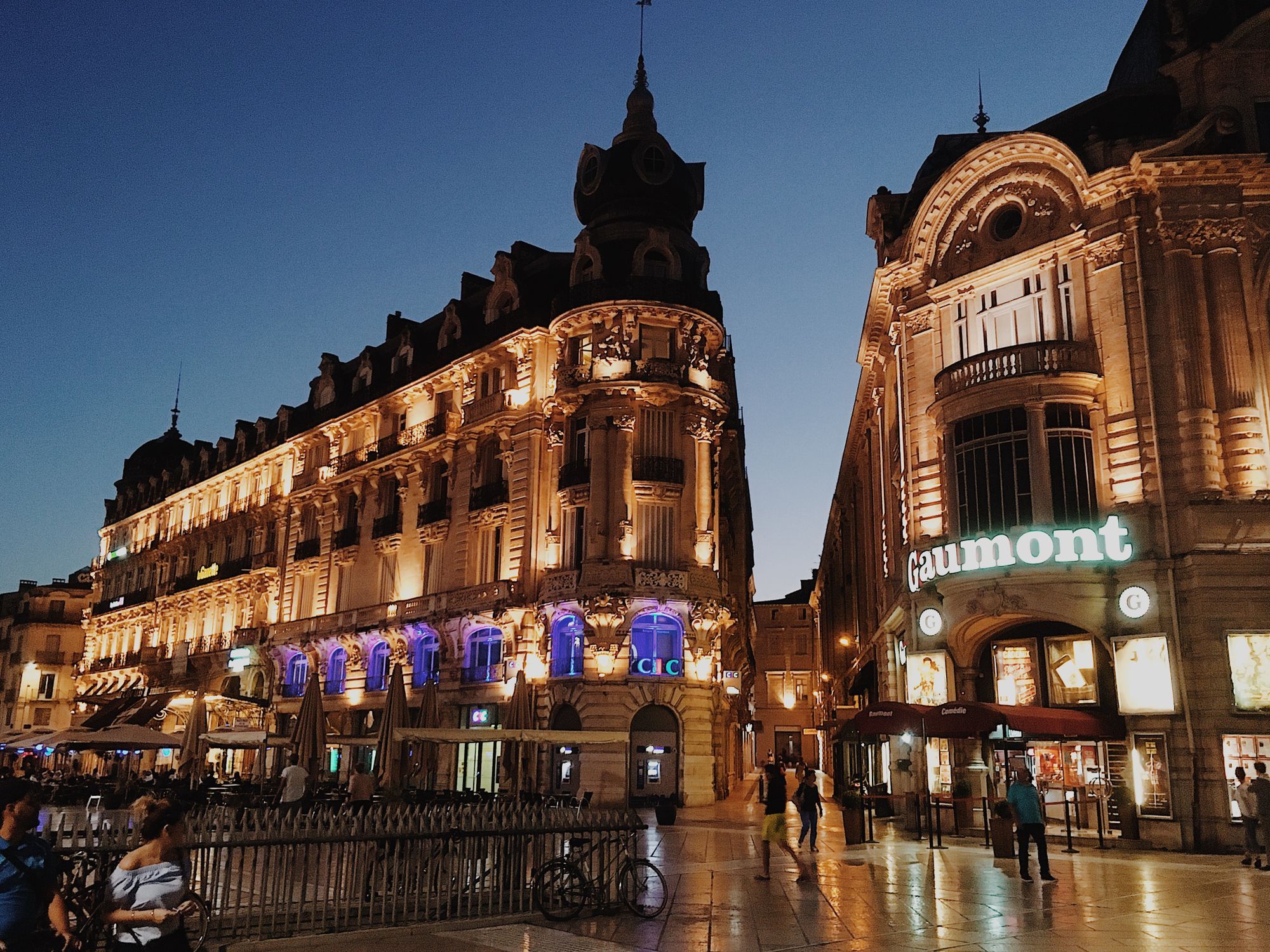 Illuminated buildings on the Place de la Comédie in Montpellier at dusk.