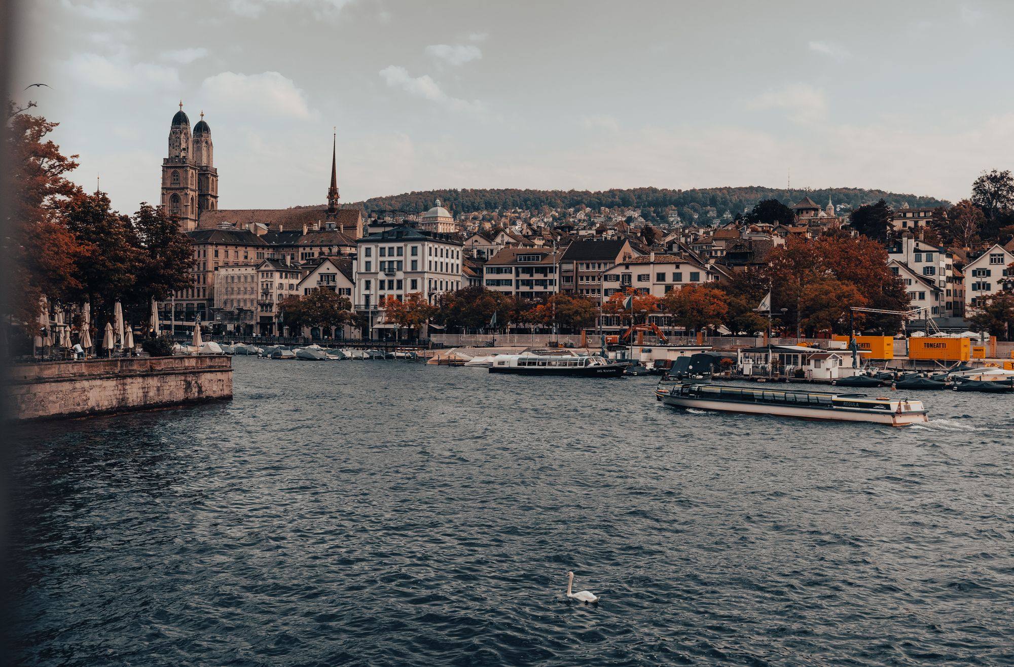 The twin towers of the Grossmünster above the old town on the Limmat in Zurich, with a boat on the water.