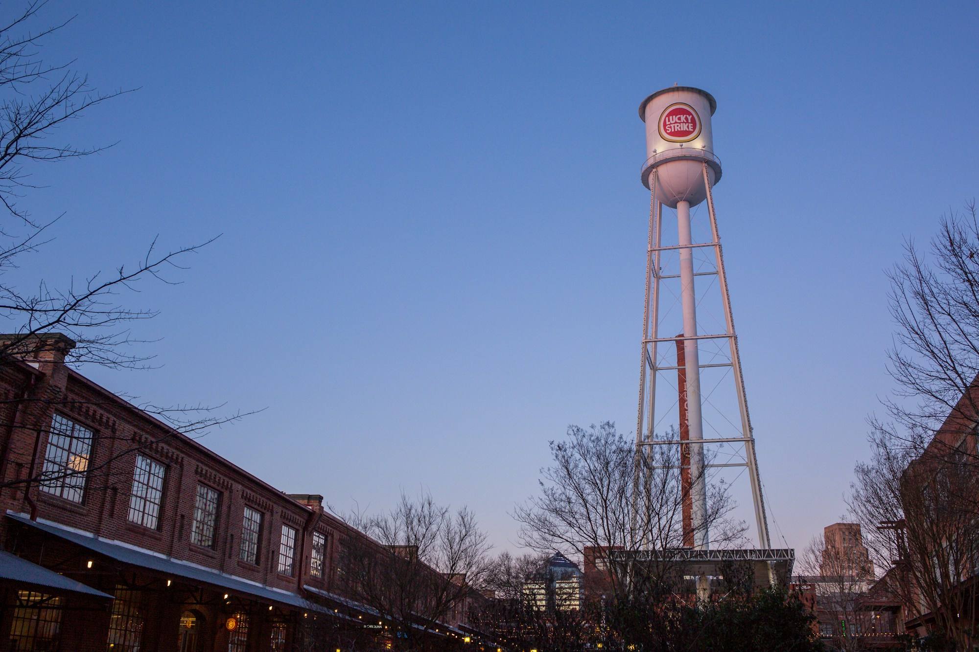 The Lucky Strike water tower above the old tobacco warehouses in Durham at dusk