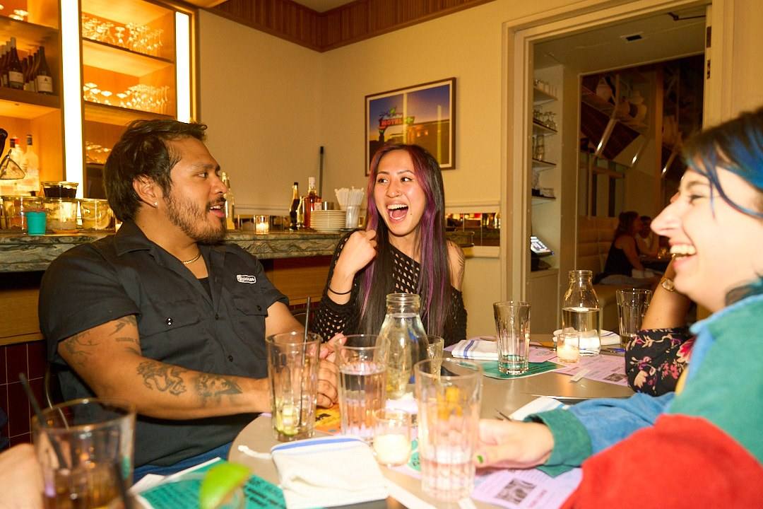 Three guests laughing at a round table at a Timeleft dinner