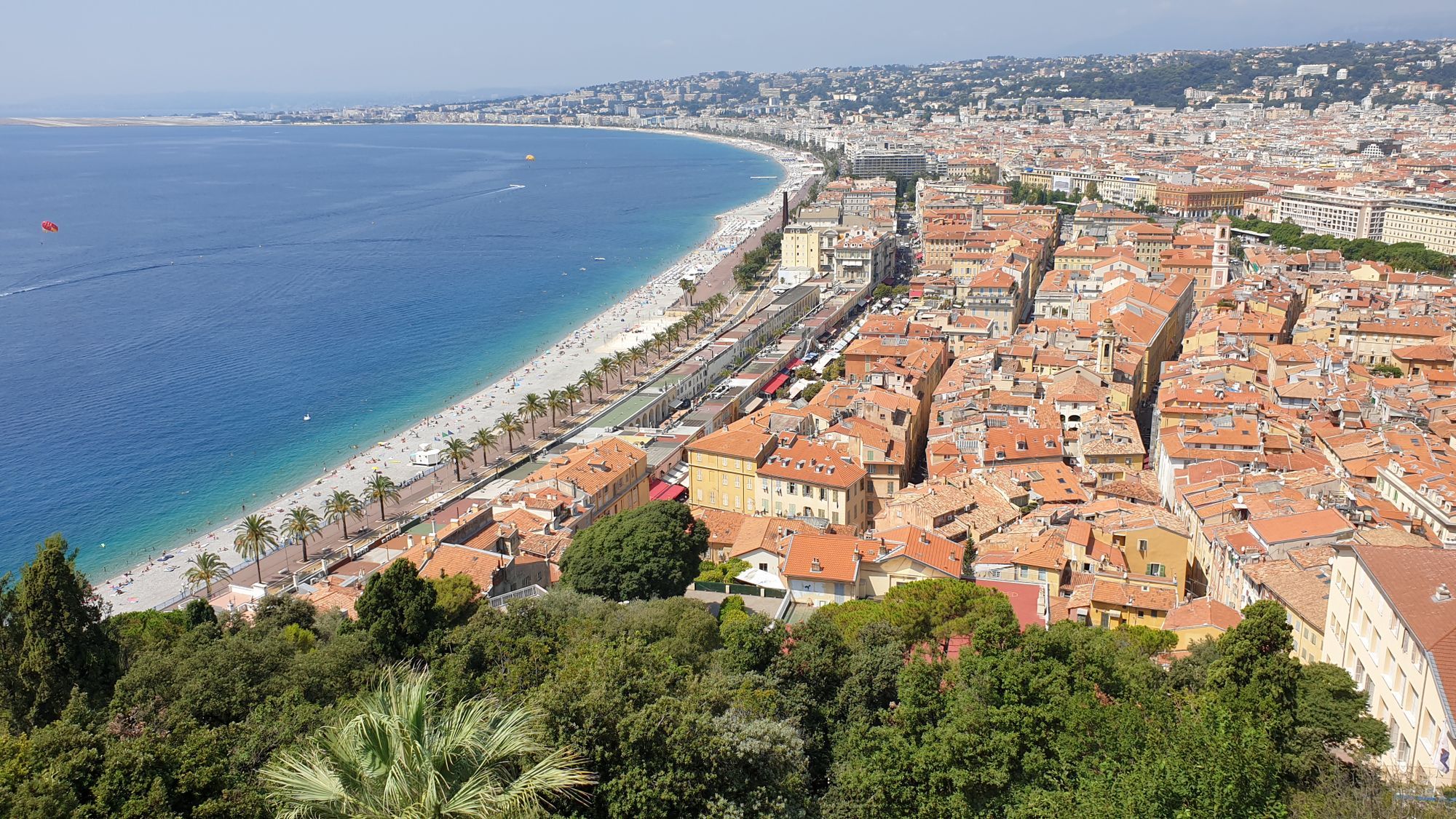 The Promenade des Anglais curving along the Baie des Anges beside the terracotta roofs of old Nice.
