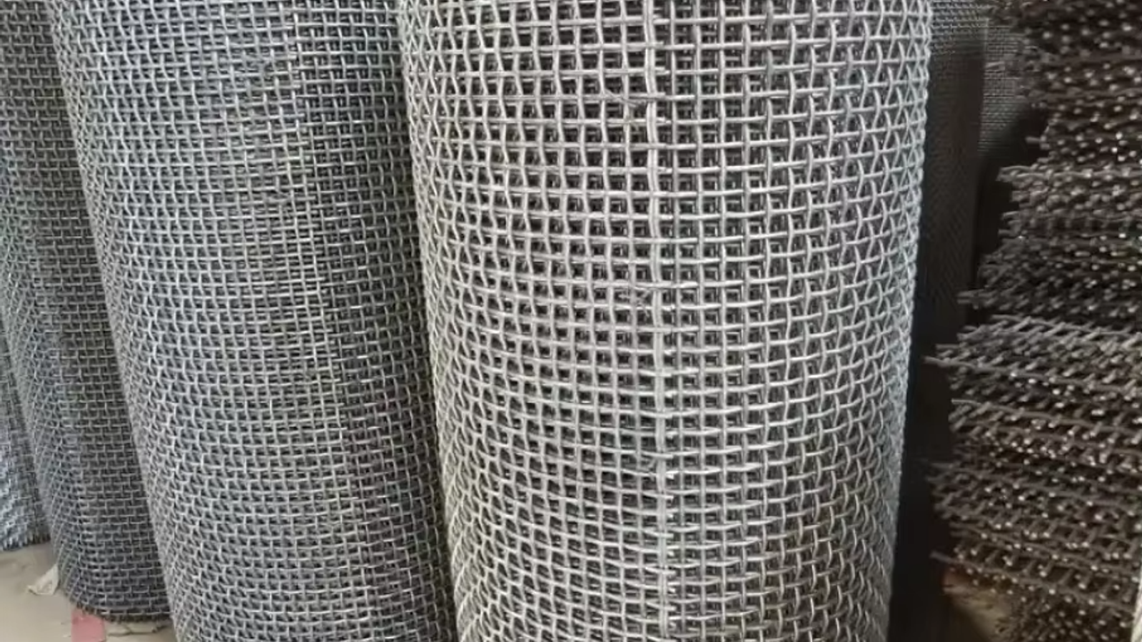 Close-up of double-crimp stainless steel woven wire mesh showing interlocked square apertures and reinforced edges on a vibrating screen deck