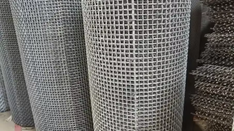 Close-up of double-crimp stainless steel woven wire mesh showing interlocked square apertures and reinforced edges on a vibrating screen deck