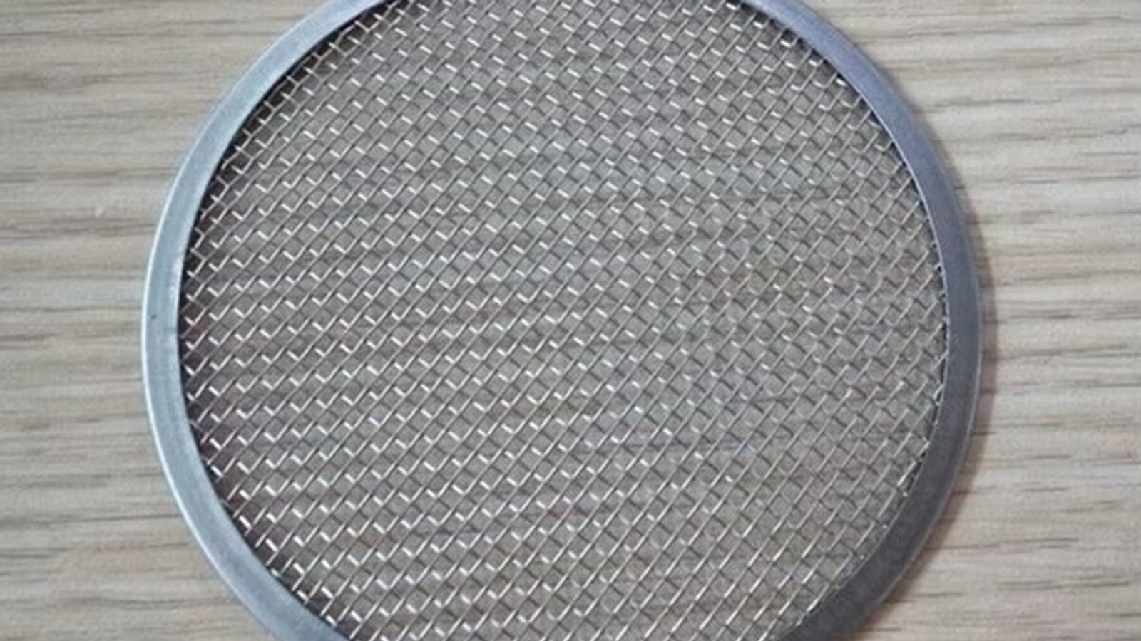 Stainless steel rimmed wire mesh filter disc for plastic extrusion, showing the welded metal edge that seals the screen changer