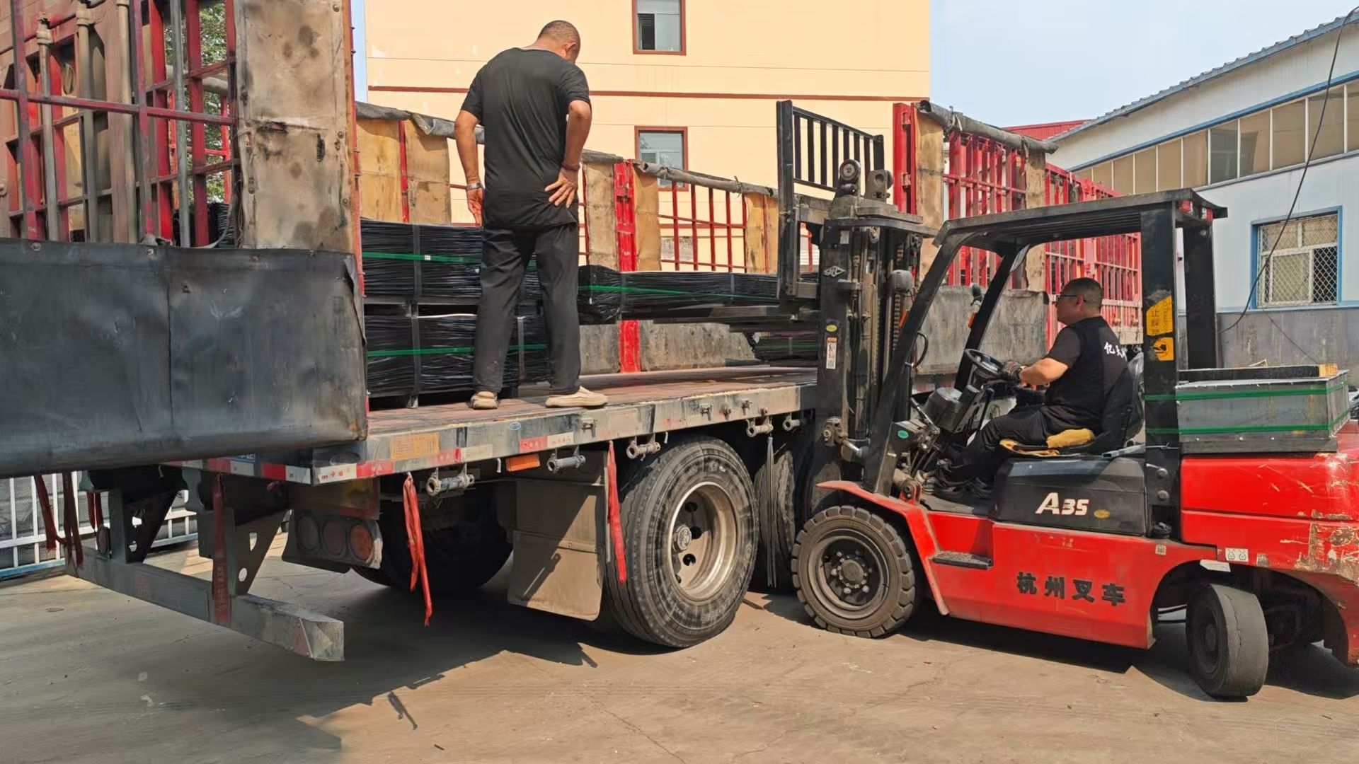 Factory forklift loading strapped wire mesh bundles onto an export truck
