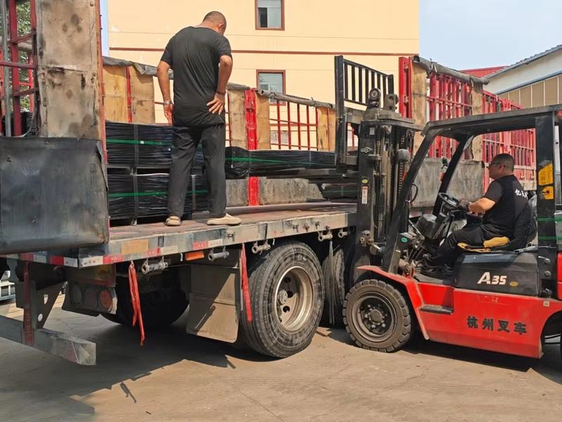 Factory forklift loading strapped wire mesh bundles onto an export truck