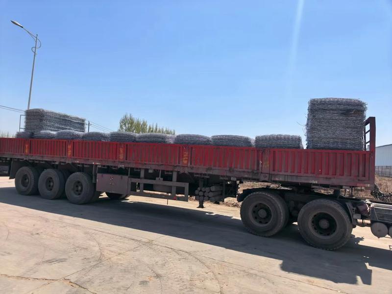 Flatbed truck loaded with wrapped wire mesh rolls leaving the factory