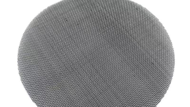Close-up of a multi-layer extruder screen pack with breaker plate — stainless steel mesh discs used in plastic recycling melt filtration