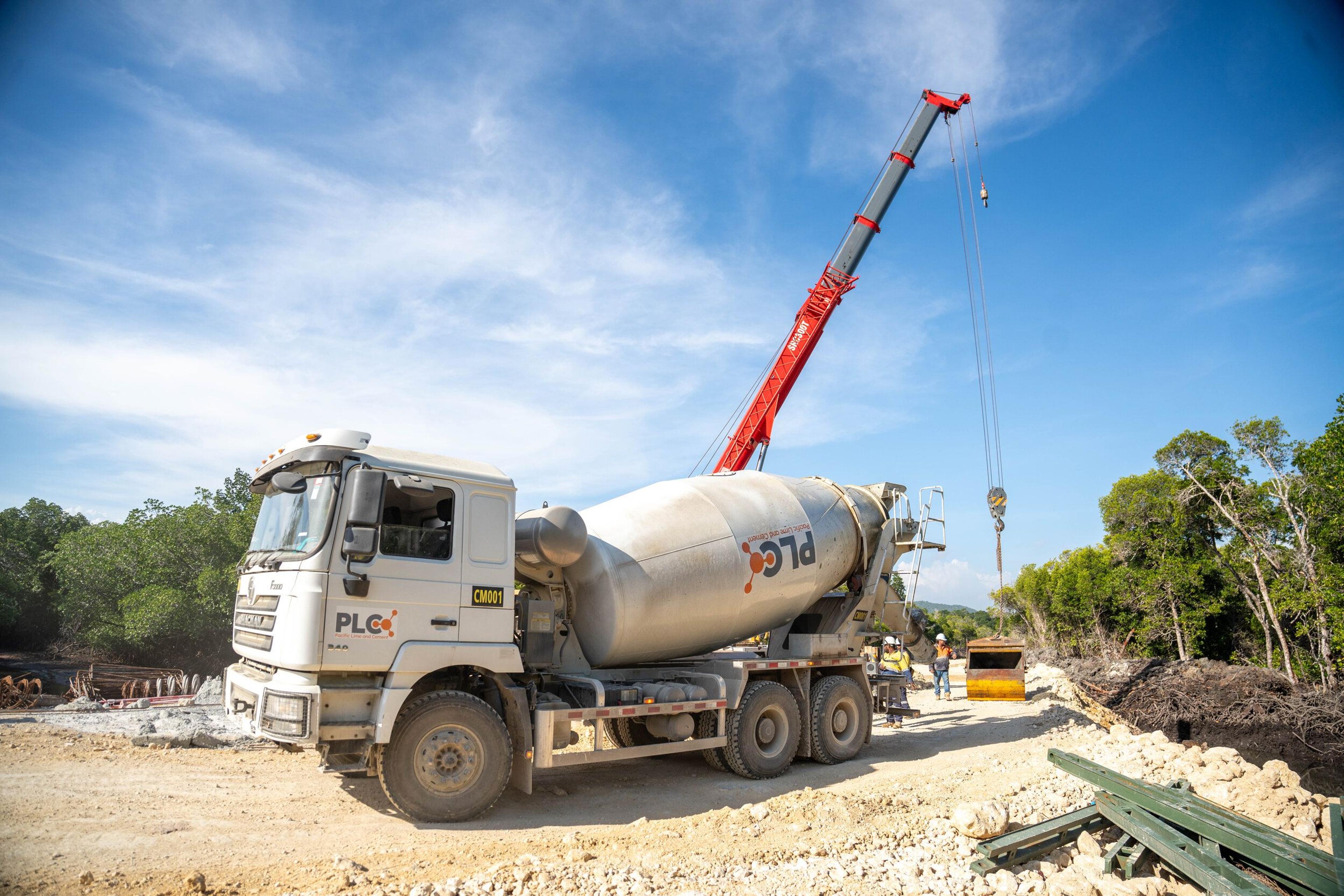 A Pacific Lime and Cement concrete agitator truck on site alongside a crane