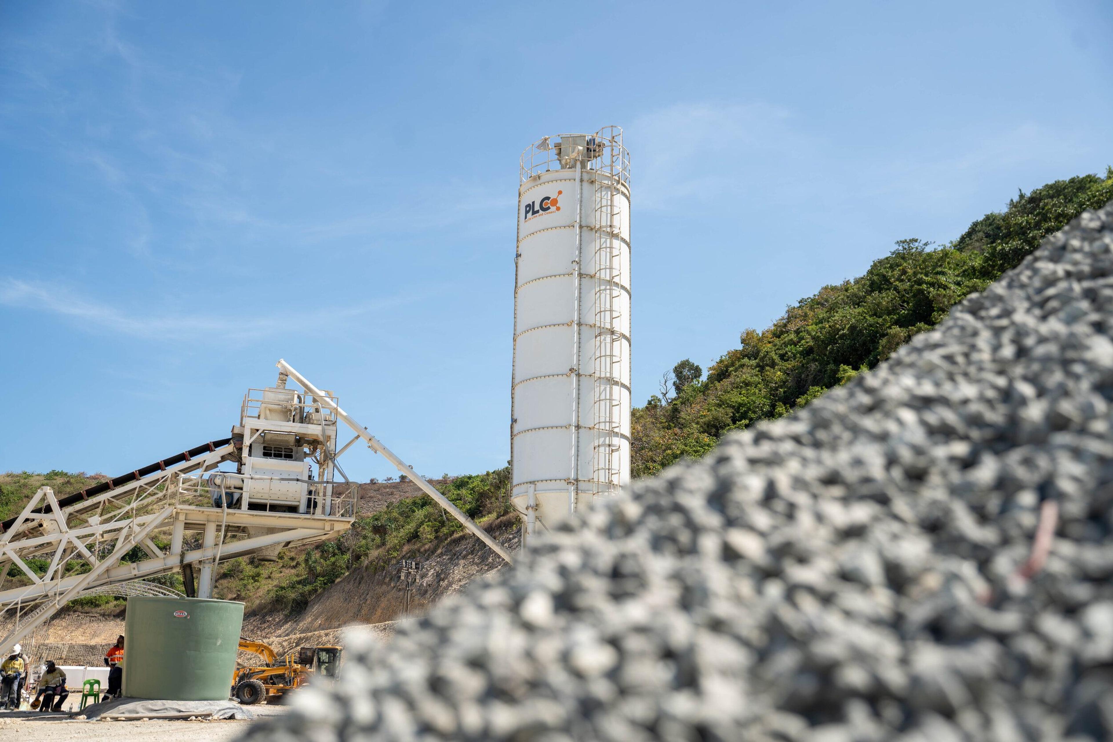 The concrete batch plant with an aggregate stockpile in the foreground