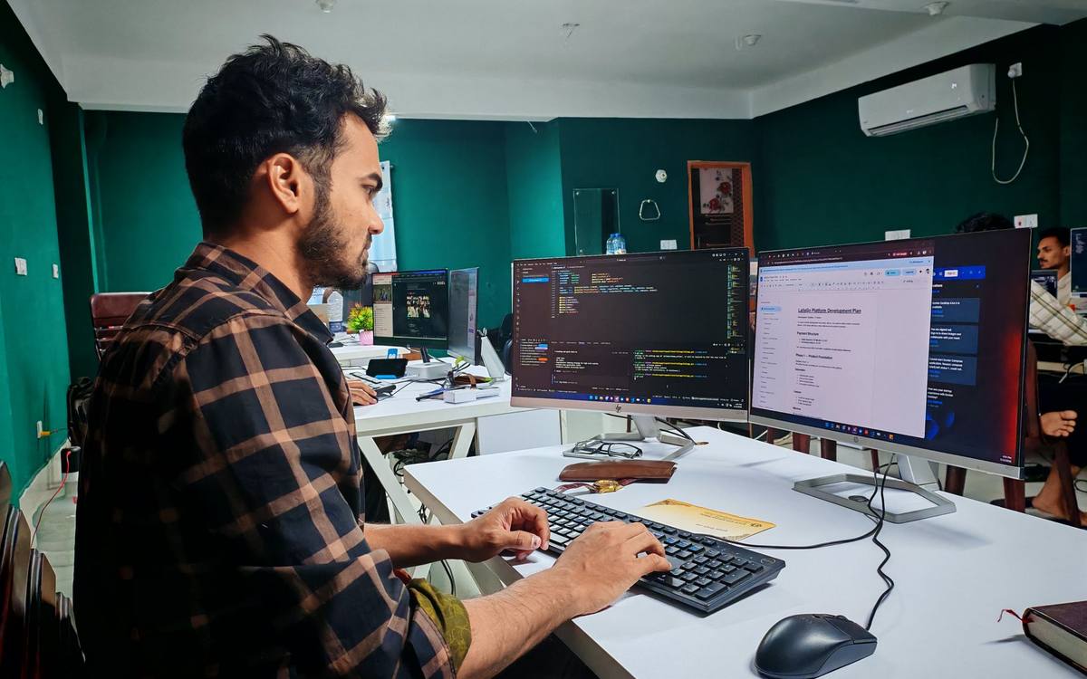 A developer working at code on multiple monitors in a dark room