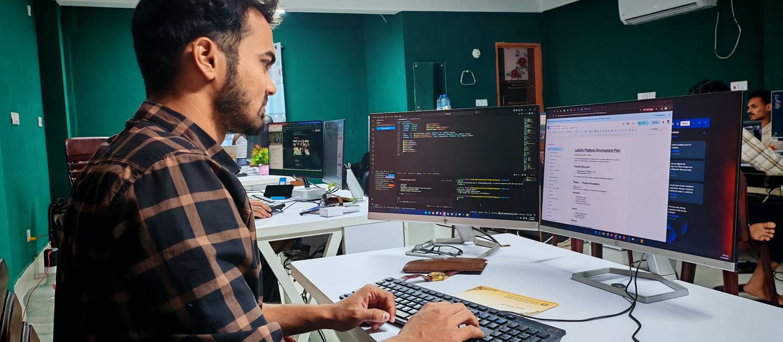 A developer working at code on multiple monitors in a dark room