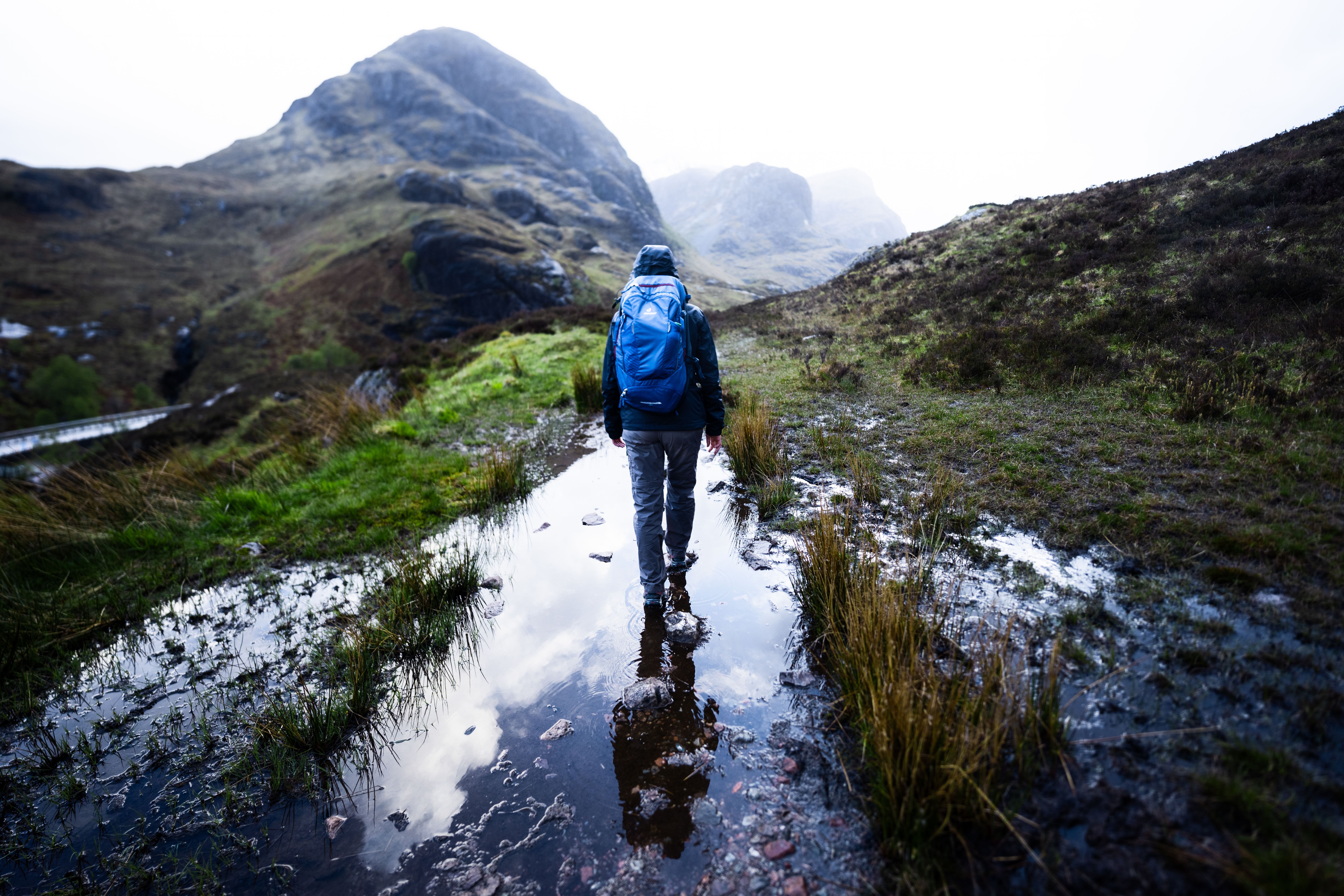 A woman hiking through the foggy mountains of Glencoe