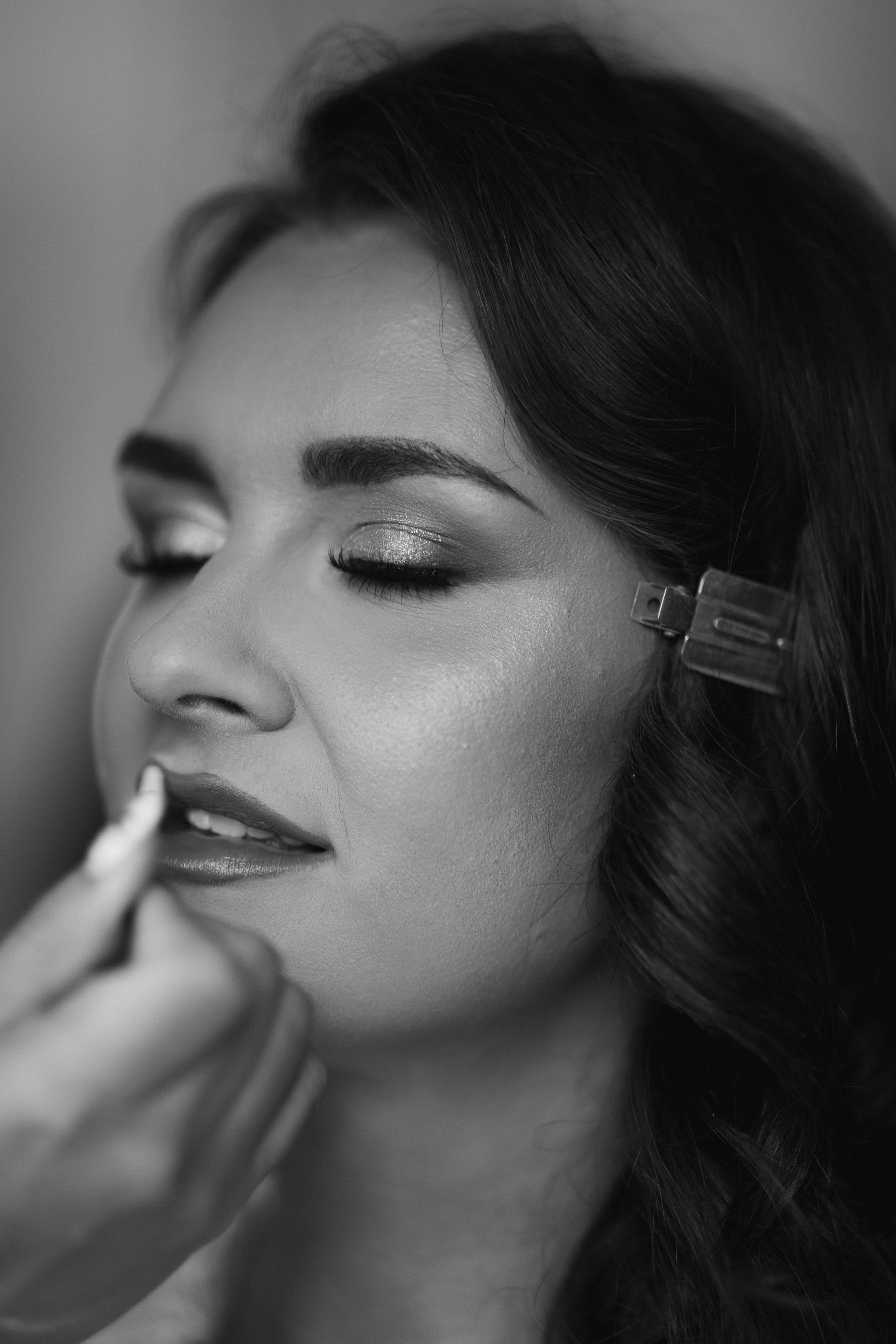 bride with eyes closed while mua applies lipstick