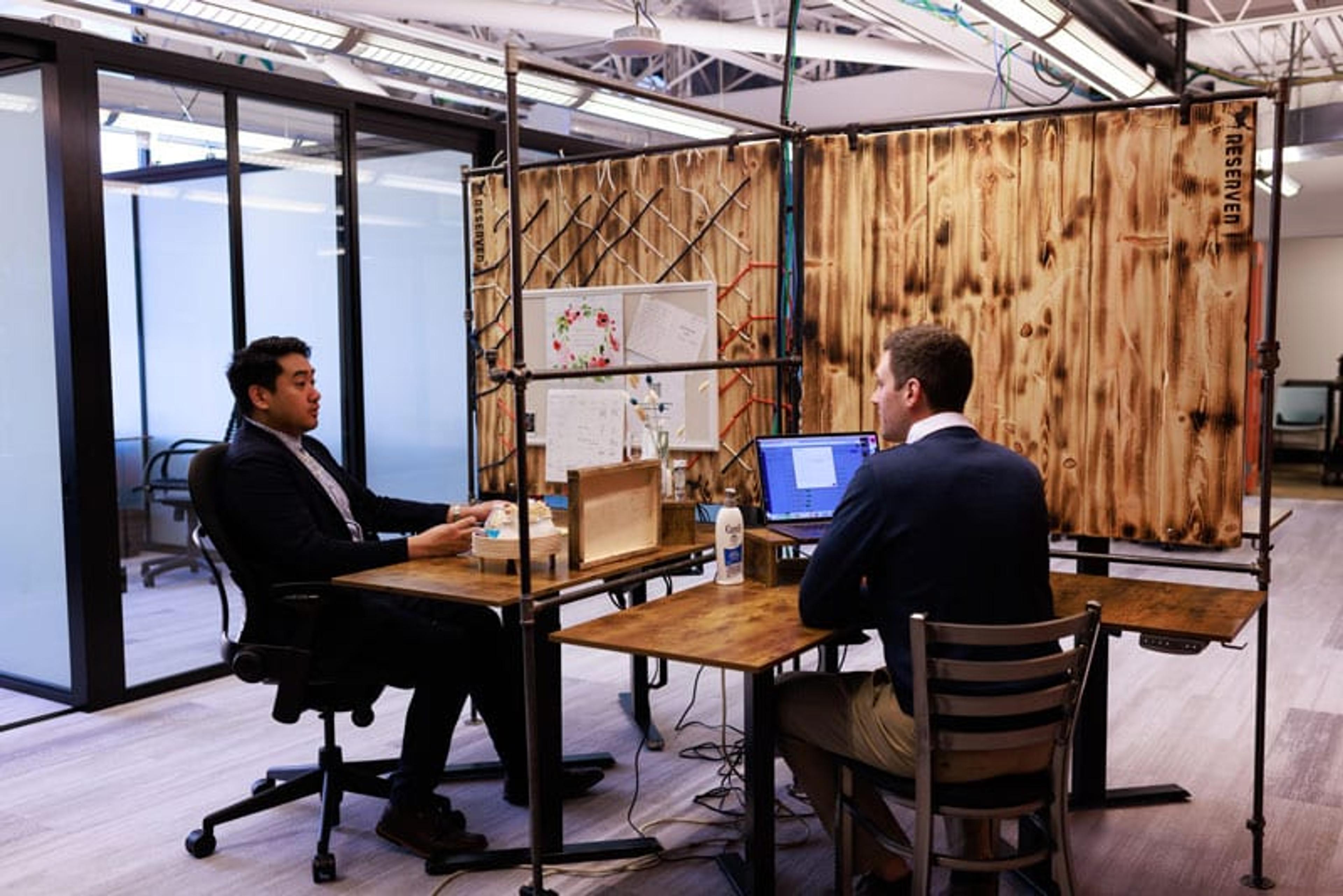 Two workers in open cubicles