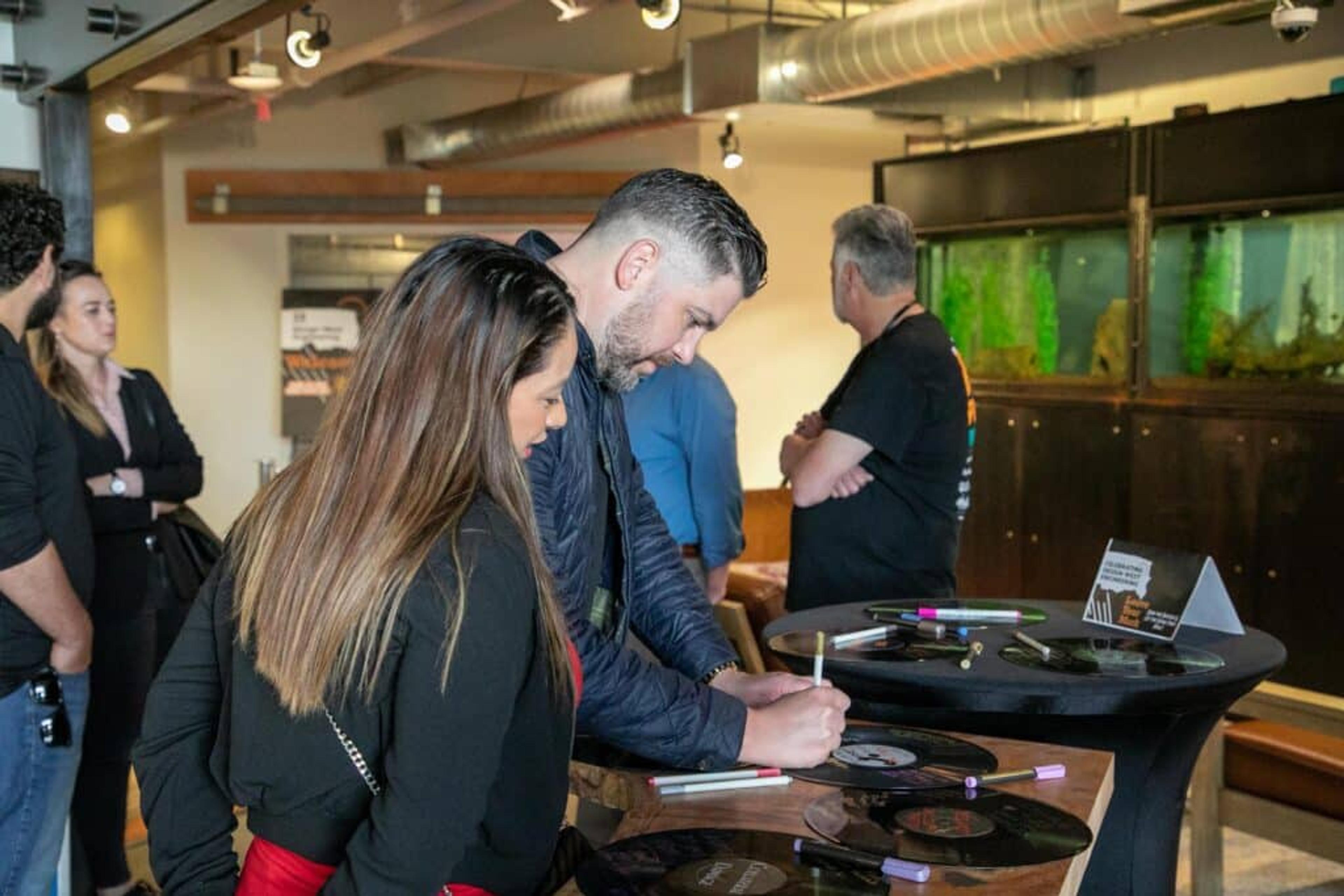 Two people signing vinyl at Workhorse event