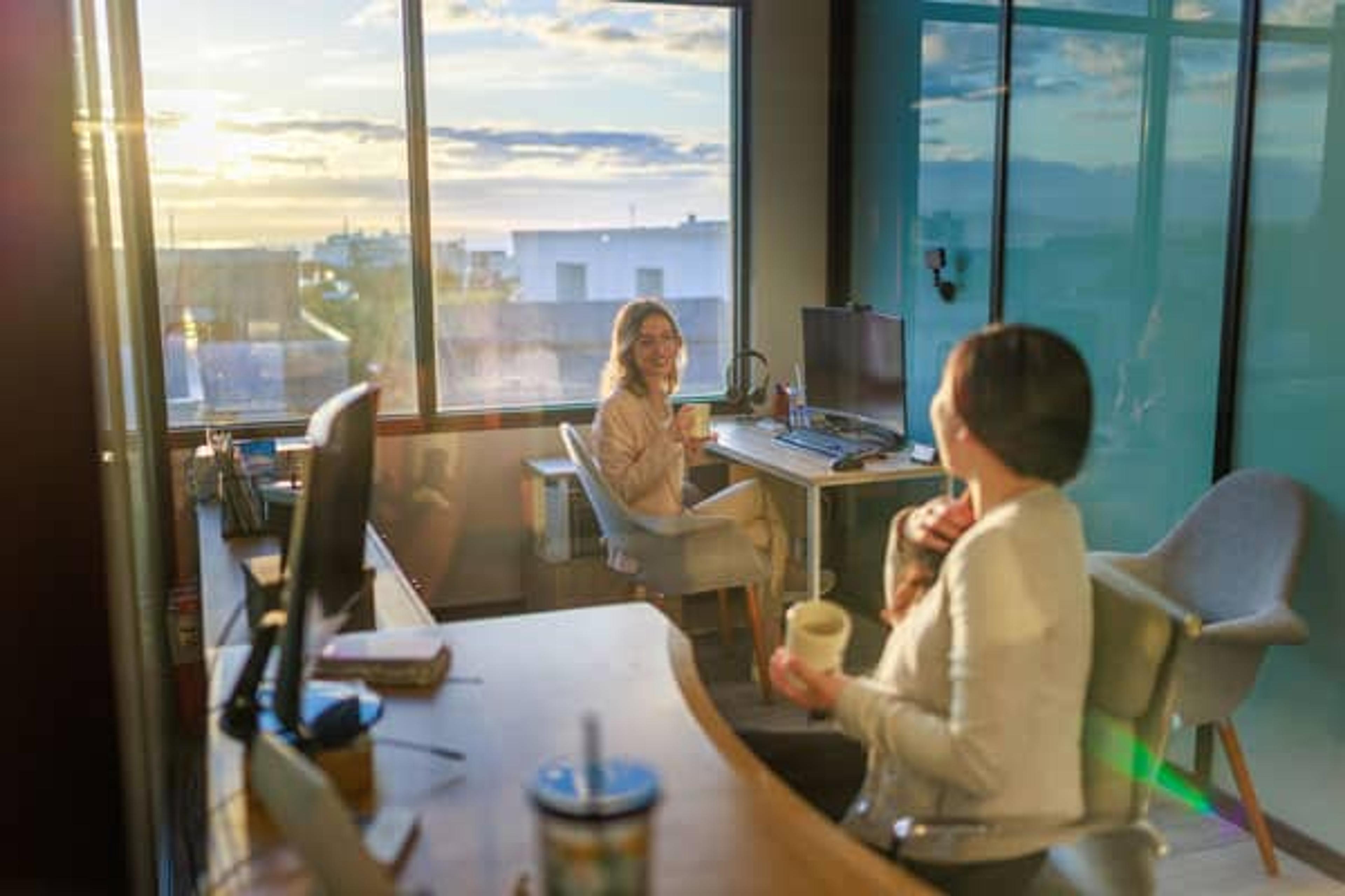 two co-workers having conversation at their work desks