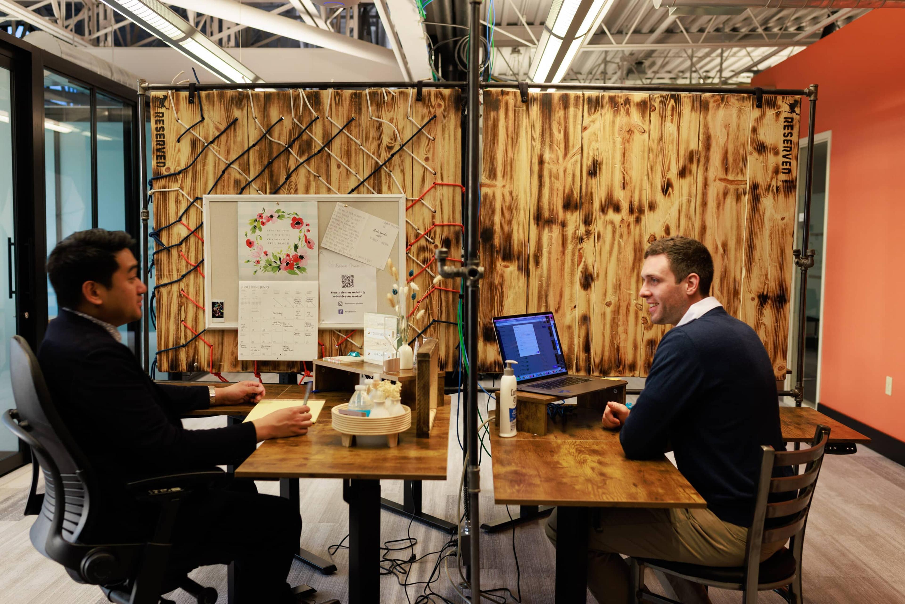 Two desk mates chatting with each other as they work.