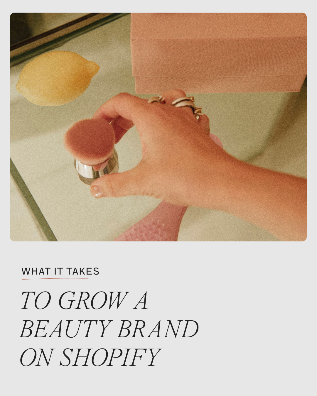 Woman applying blush at a mirrored vanity with a jade roller and lemon