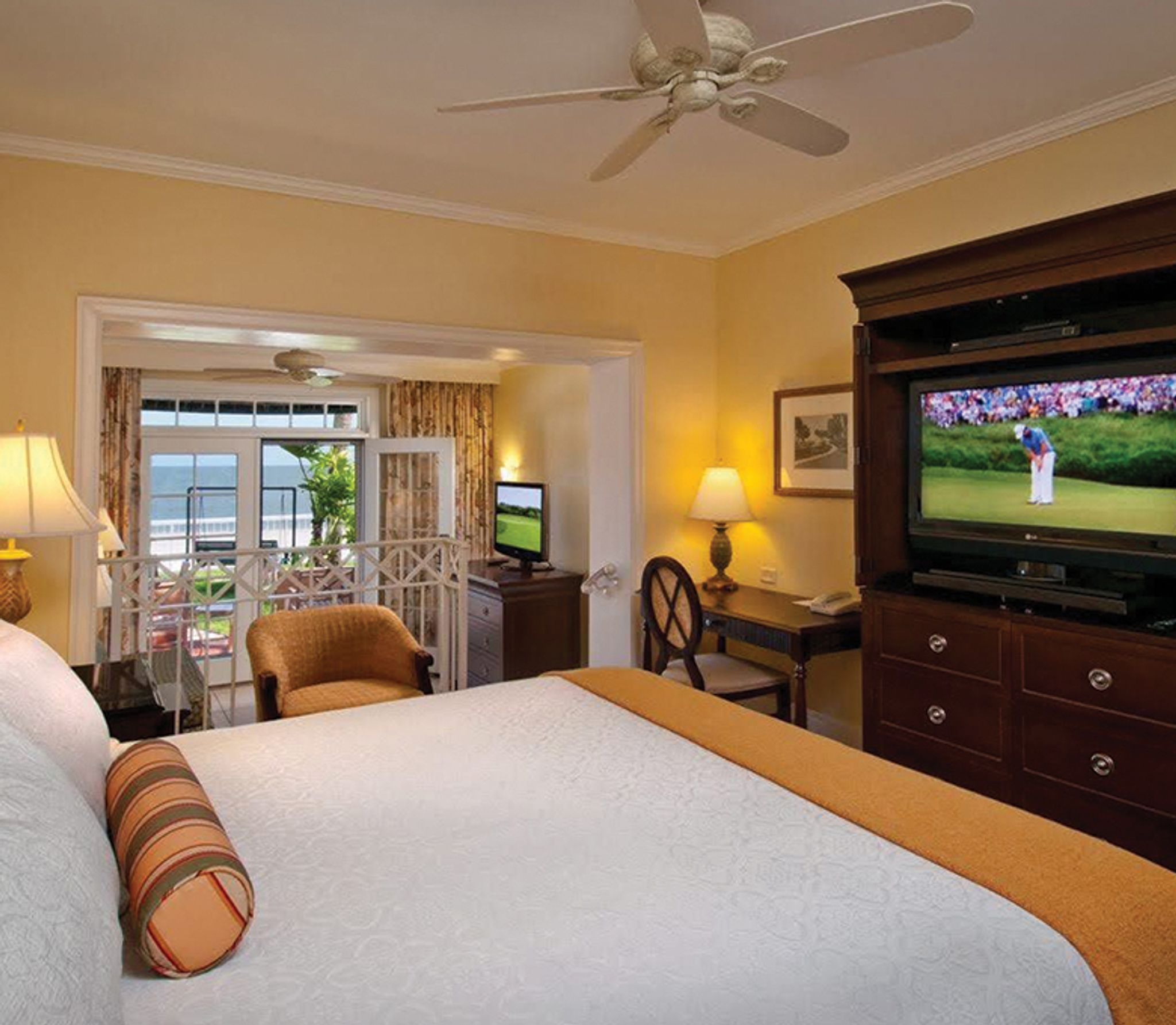 king bed in a spacious bedroom with a tv showing a golf tournament