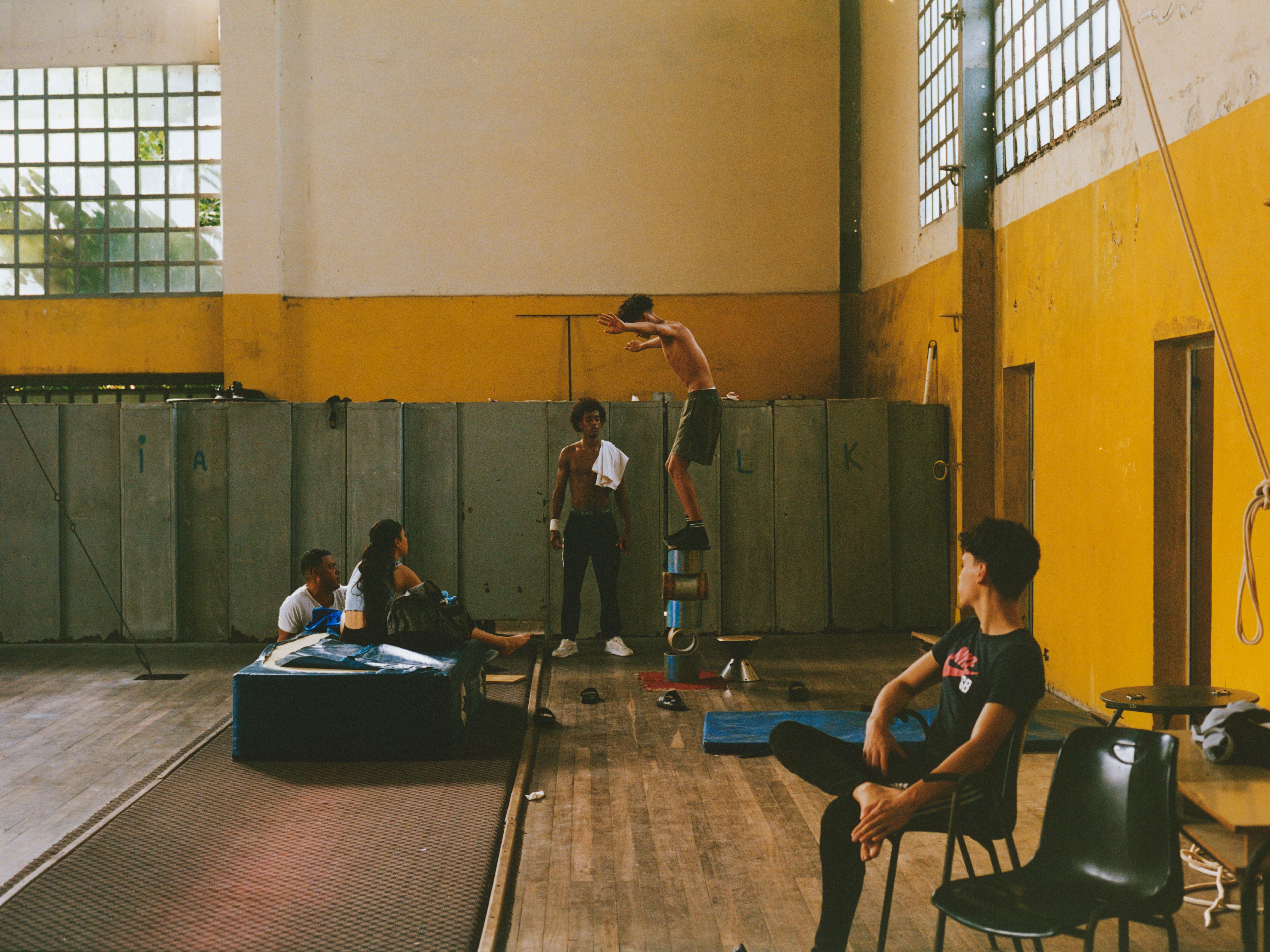 A rehearsal before final exams takes place in the Escuela Nacional de Circo’s main space, where a single classroom and open practice area serves as the heart of student life—hosting rehearsals, stretching, acrobatics training, and also housing the stretching table, makeup and hair prep area, and lockers. Despite the aged facilities, minimal modern equipment, and reliance on natural daylight, students continue to train and perform at an impressively high level.
