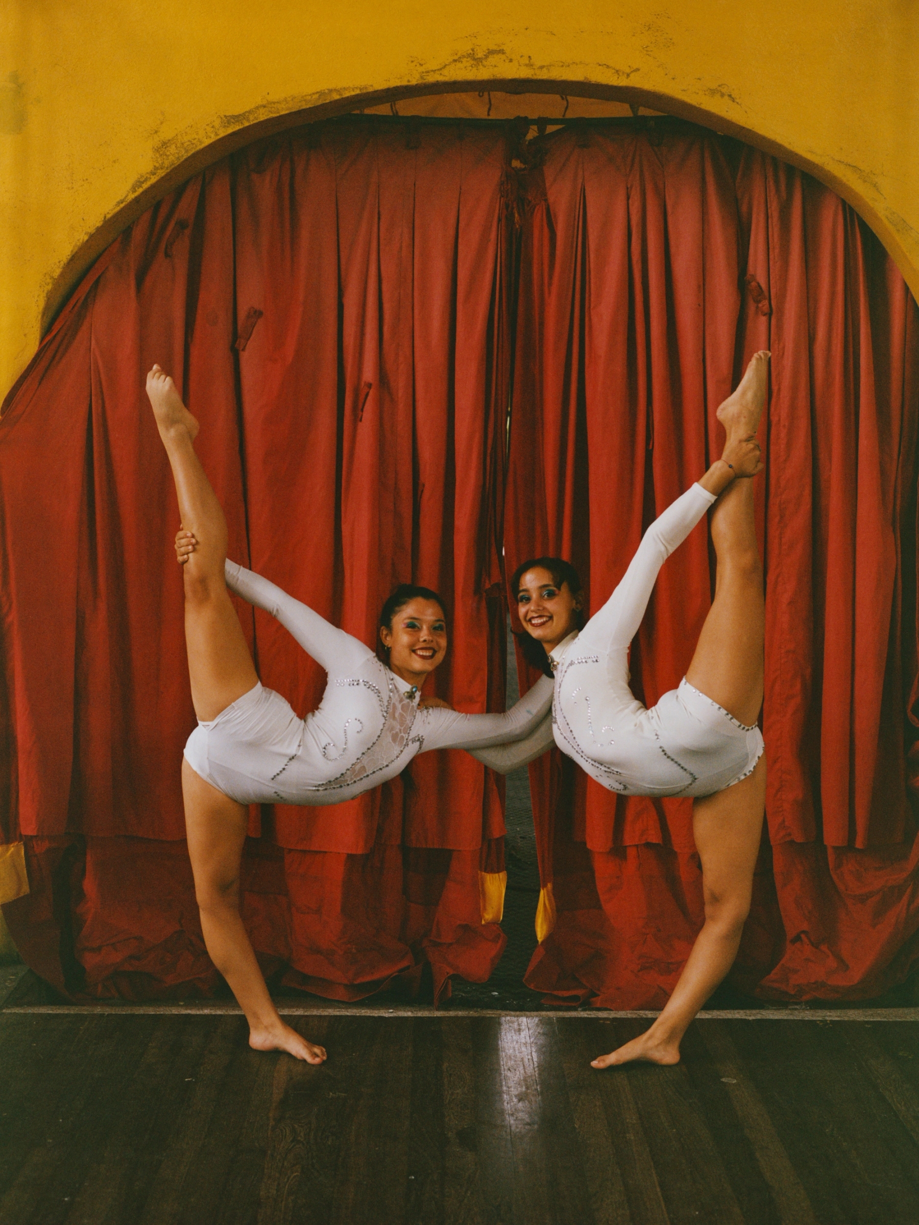 Lauren Llaguno Gutiérrez and Leira Novi Castaño Risco pose before a performance. Duo acts are central to Cuban circus arts, emphasizing trust, synchronization and collective expression, with influences from partner dances such as salsa and rumba.
