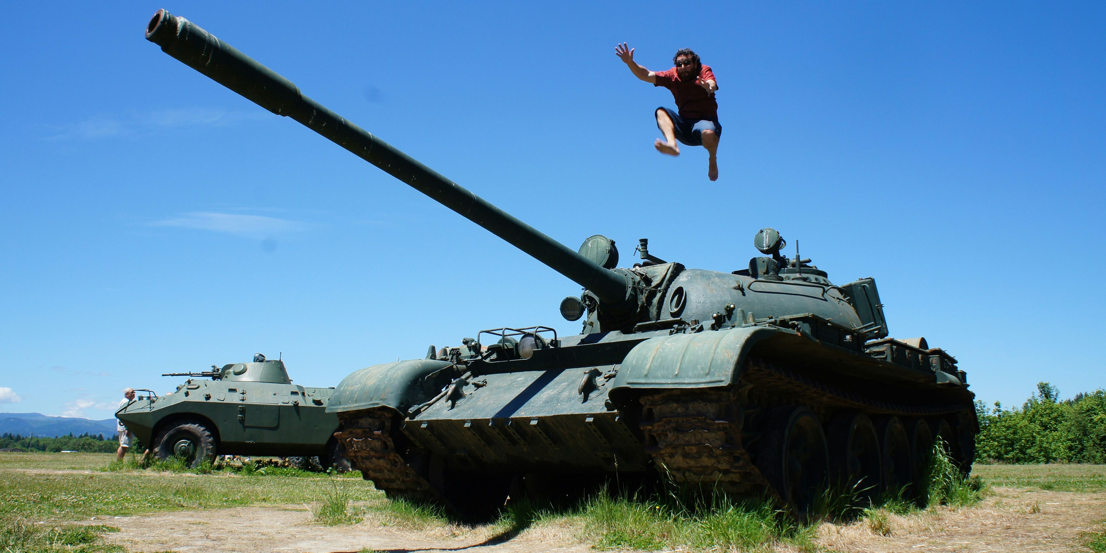 a man is jumping in the air in front of a tank .