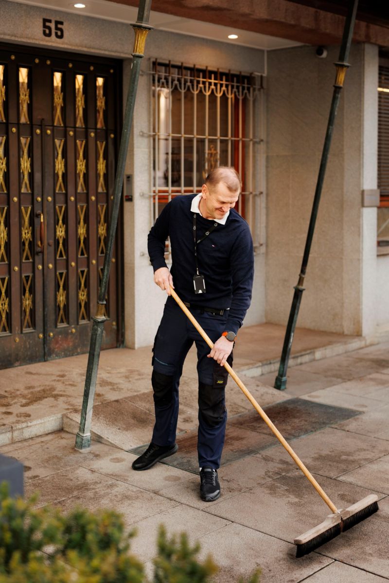 Foto av en vaktmester som koster foran inngangspartiet til et kontorbygg