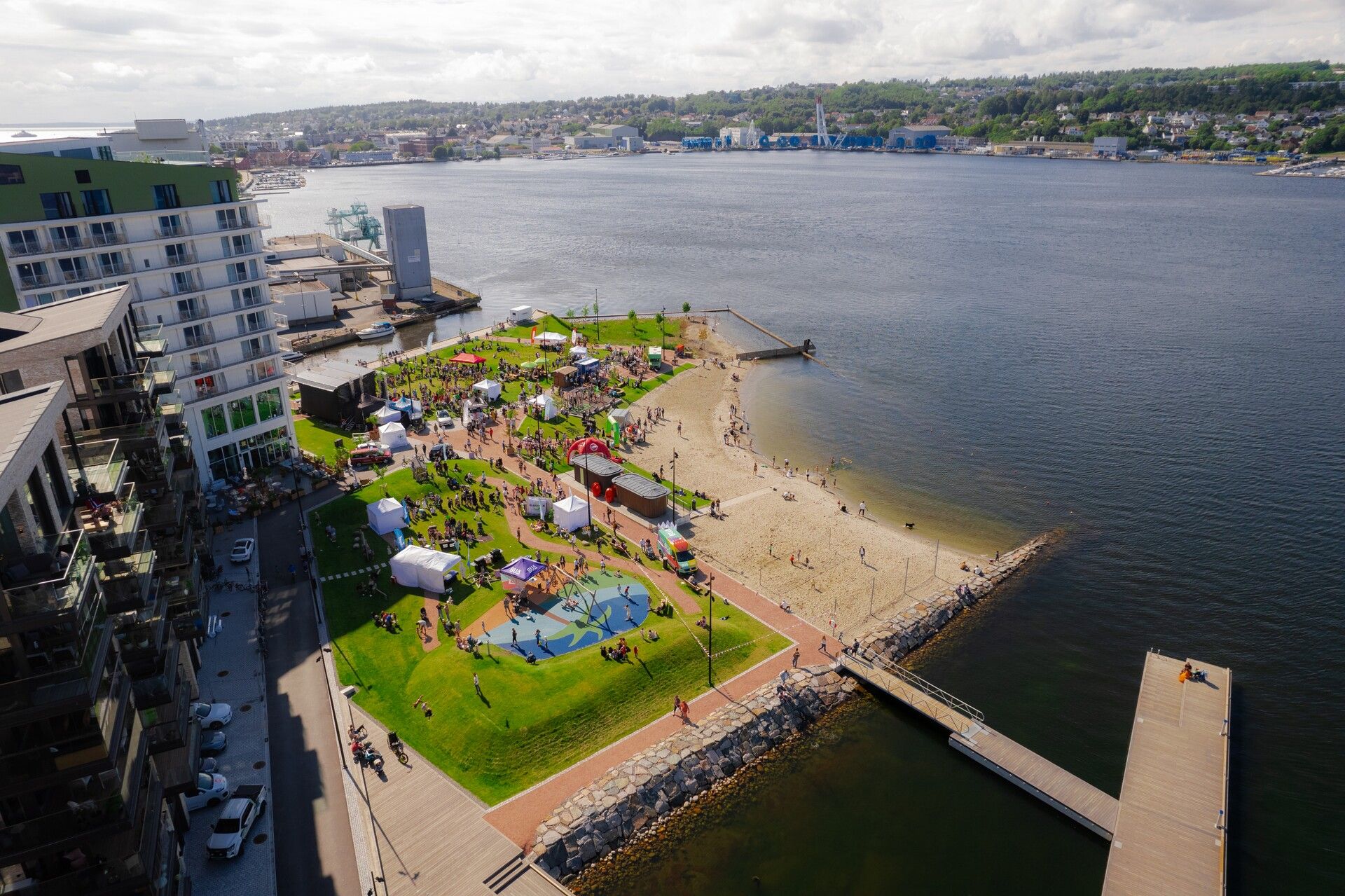 Rabben sett ovenfra med drone. bildet viser en strand, gress og masse mennesker i parken