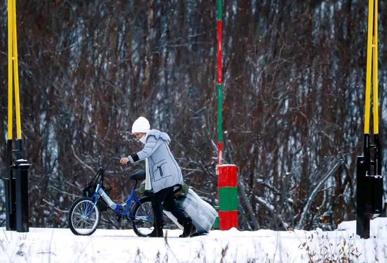 En kvinne med sykkel og koffert passerer den norsk-russiske grensen på Storskog i Finnmark i 2015.