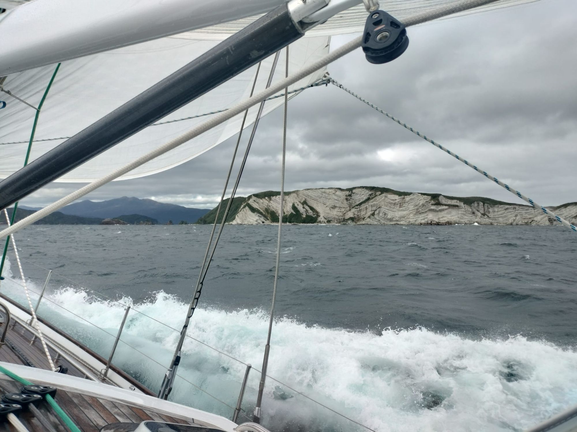 Matariki III sailing past the dramatic white chalk cliffs and rocky foreshore of Chalky Island in breezy conditions
