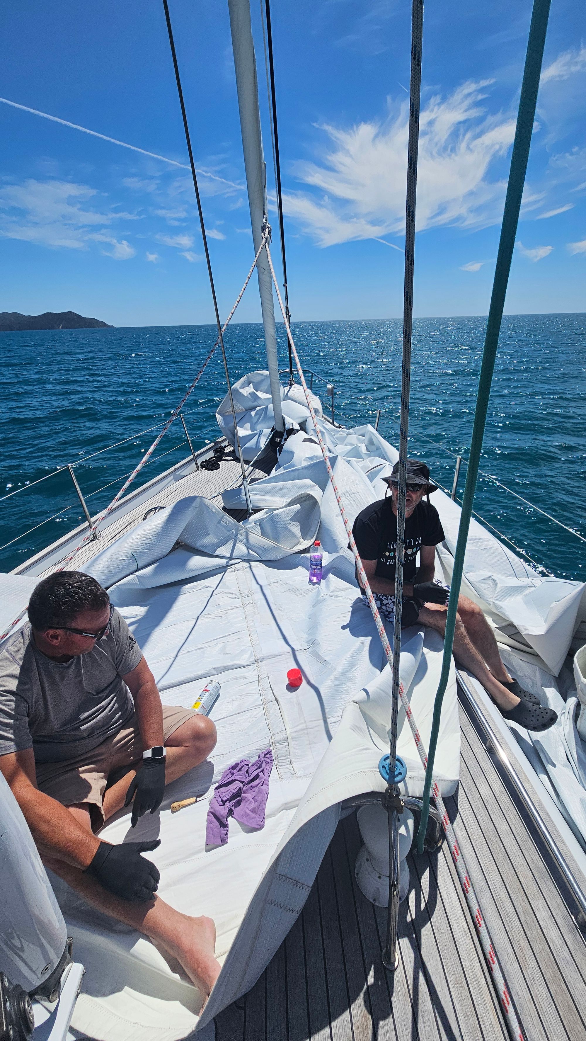 Matt and Bruce taping the unstuck seam on the mainsail spread out on deck in Tasman Bay